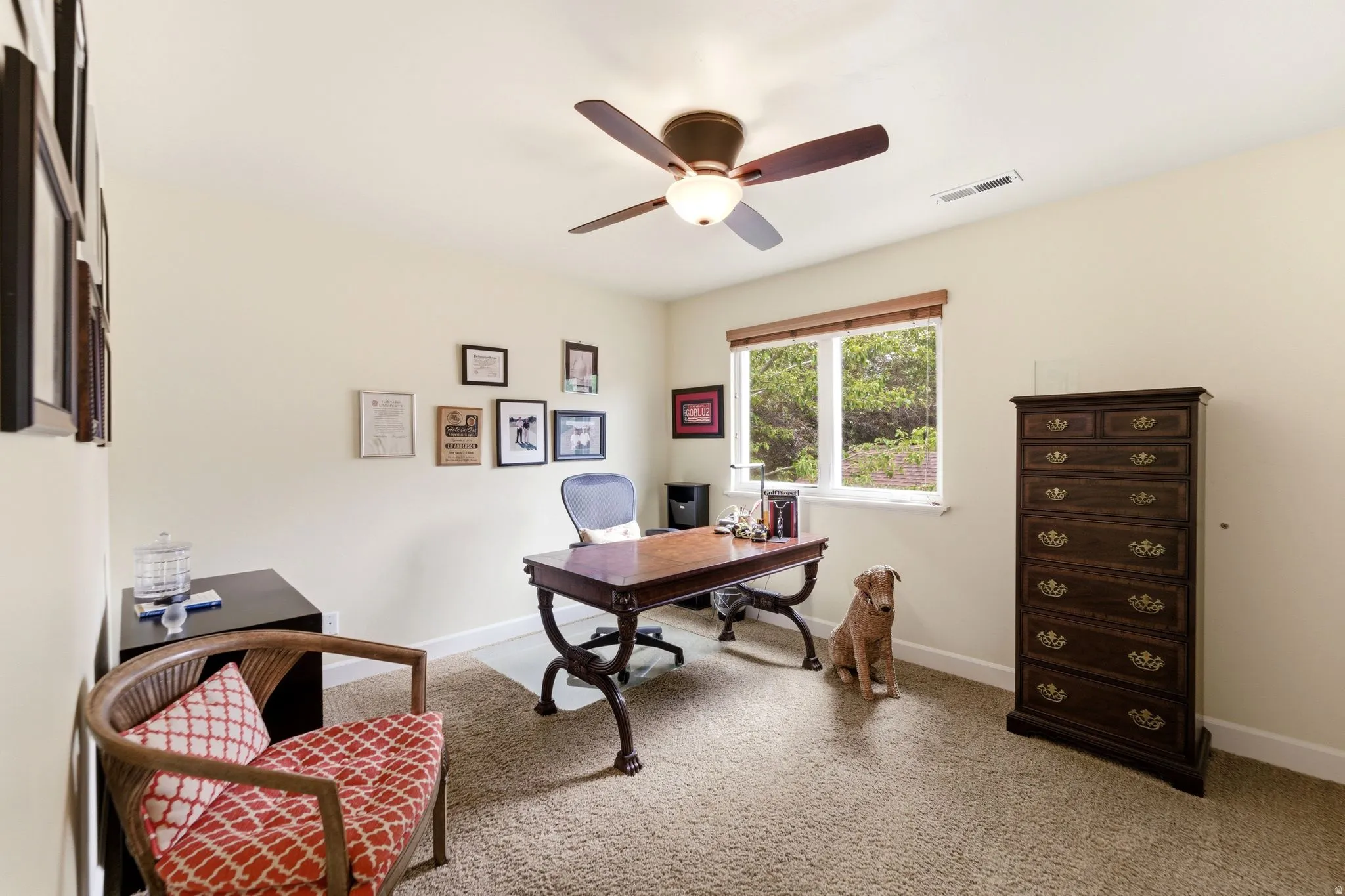Carpeted room with a ceiling fan, a window featuring wood-finish trim, and neutral-toned walls