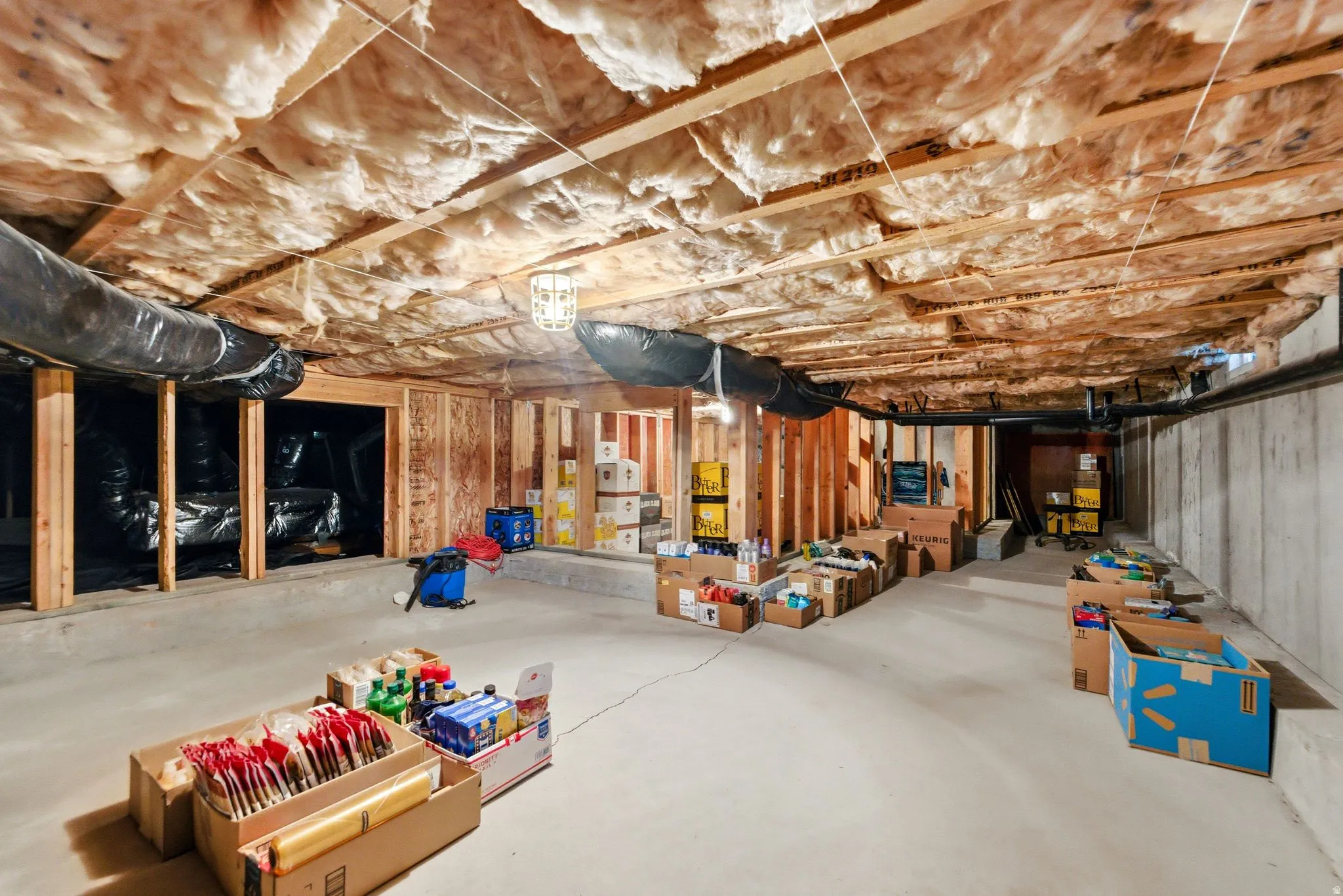 Unfinished basement featuring concrete flooring, exposed wood framing, and ceiling insulation