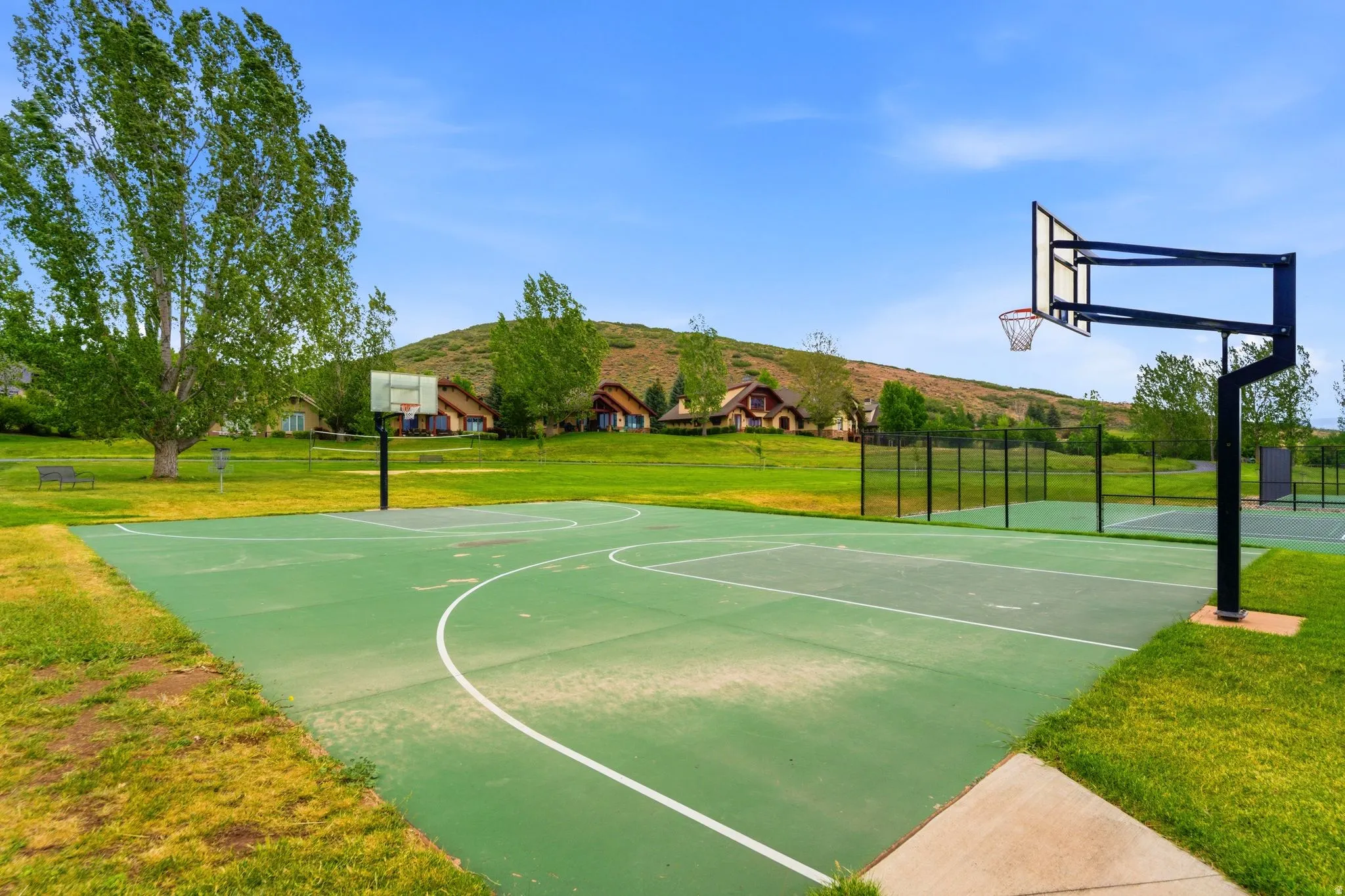 Outdoor basketball court featuring two hoops, a fenced perimeter, and a light green surface with white court linesAerial views of Burgi Hill Park adjacent to Valais