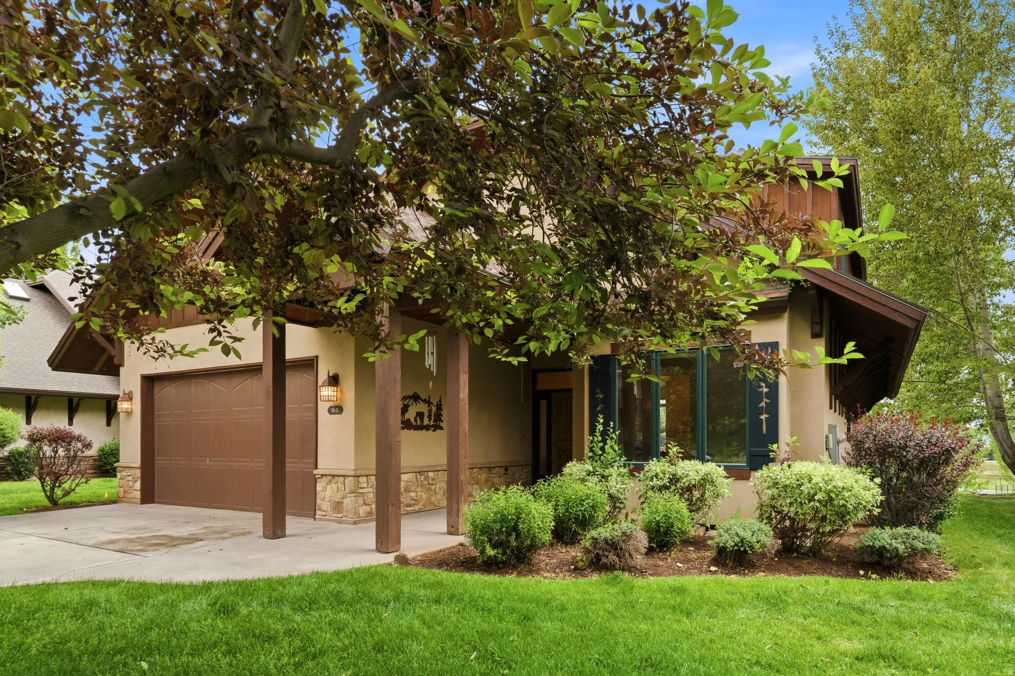 Stucco exterior featuring stone accents and a covered entry