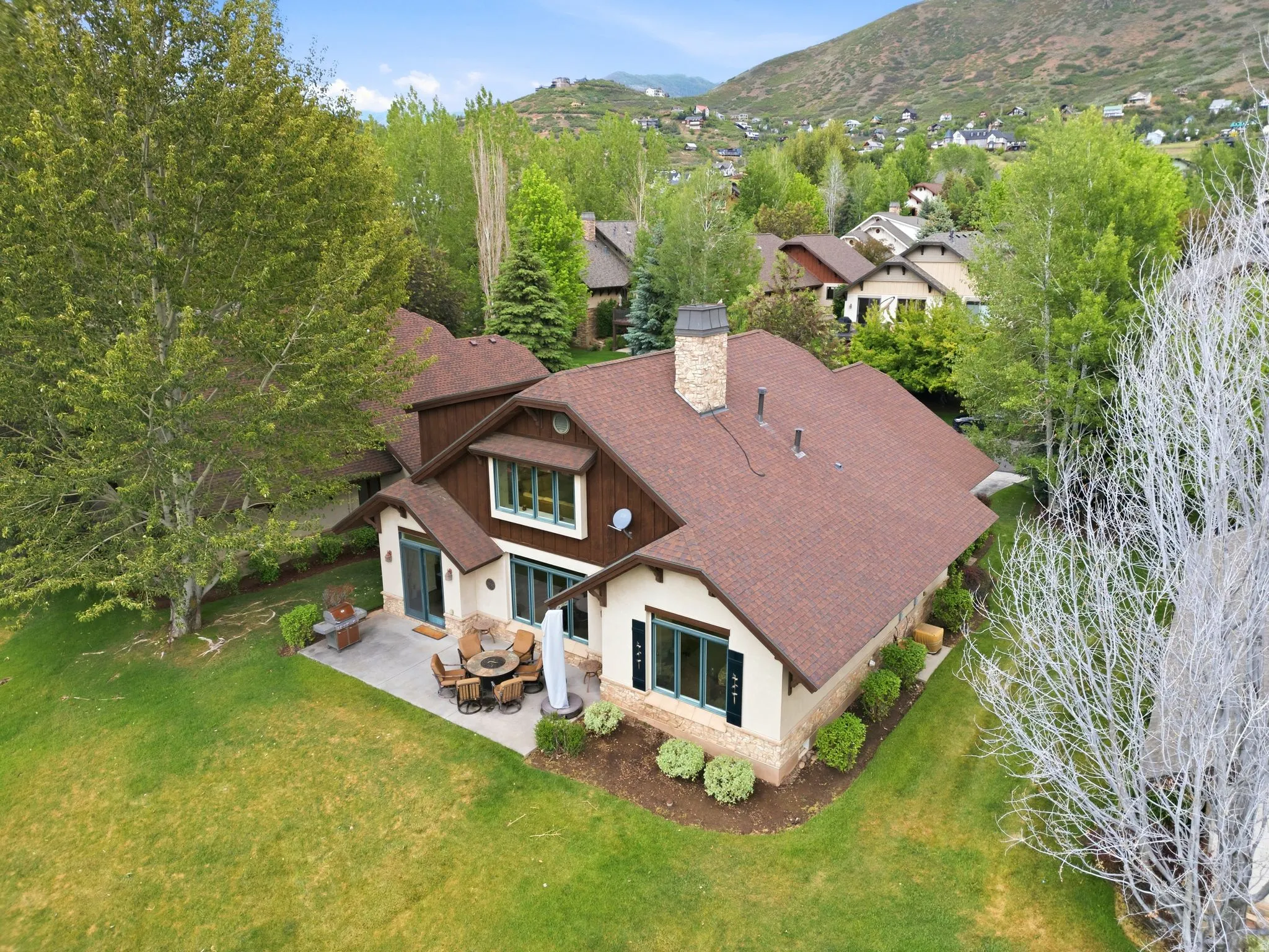 Property exterior featuring a stone chimney, brown shingle roof, and a beige stucco facade