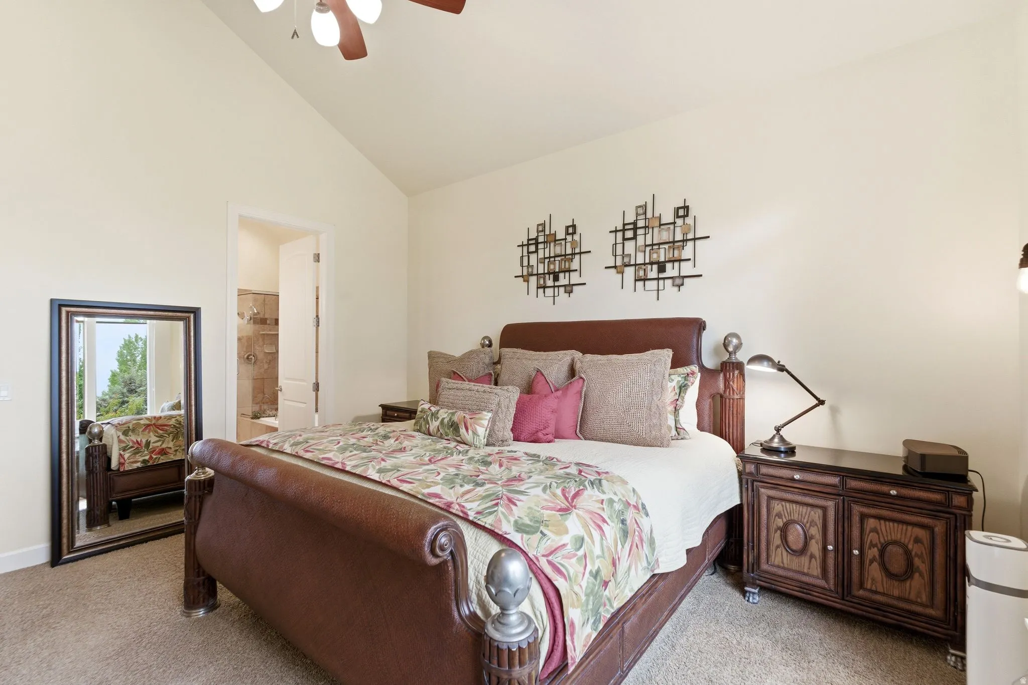 Vaulted ceiling bedroom featuring a ceiling fan with integrated lighting, neutral wall tones, and carpet flooring