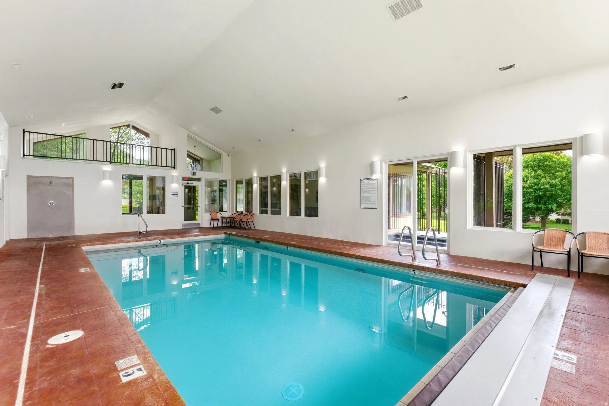Indoor swimming pool featuring a vaulted ceiling and extensive natural light from multiple windows
