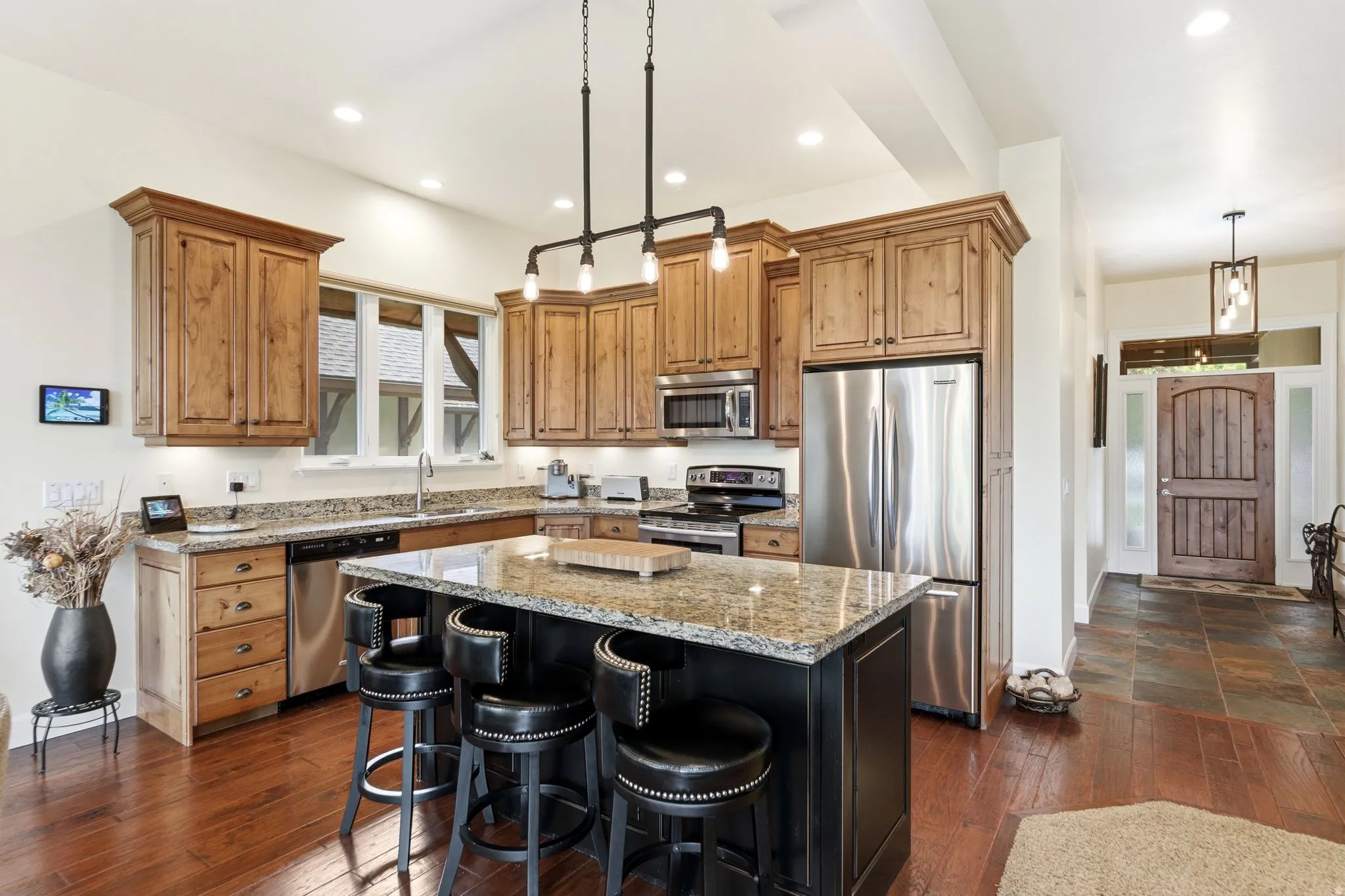 Kitchen featuring a central island with a granite countertop, stainless steel appliances, wood-finish flooring, recessed lighting, and a window above the sink