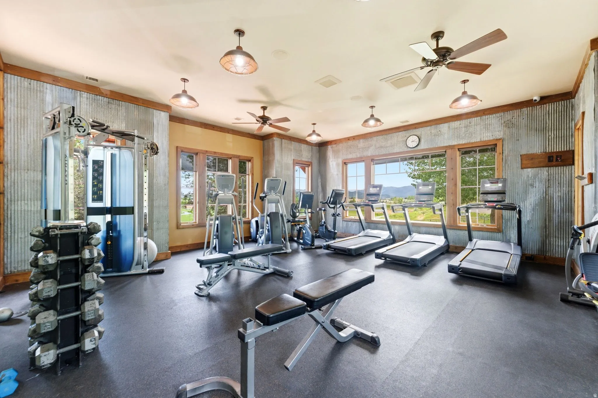 Dedicated fitness space featuring rubber flooring, corrugated metal wall accents, exposed wood trim, and multiple windows