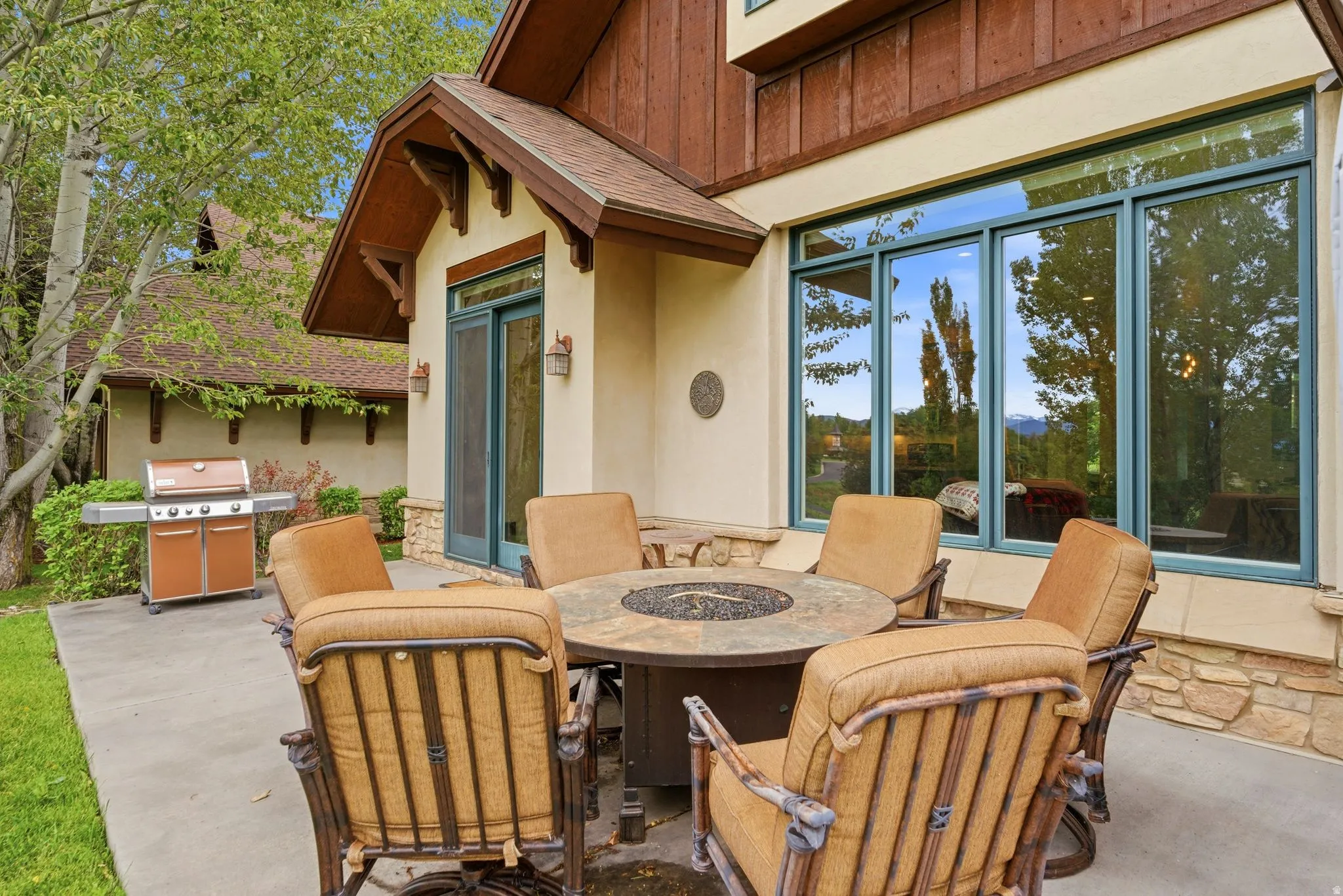 Patio area featuring a stone-clad exterior, large framed windows, and a prominent outdoor fire pit