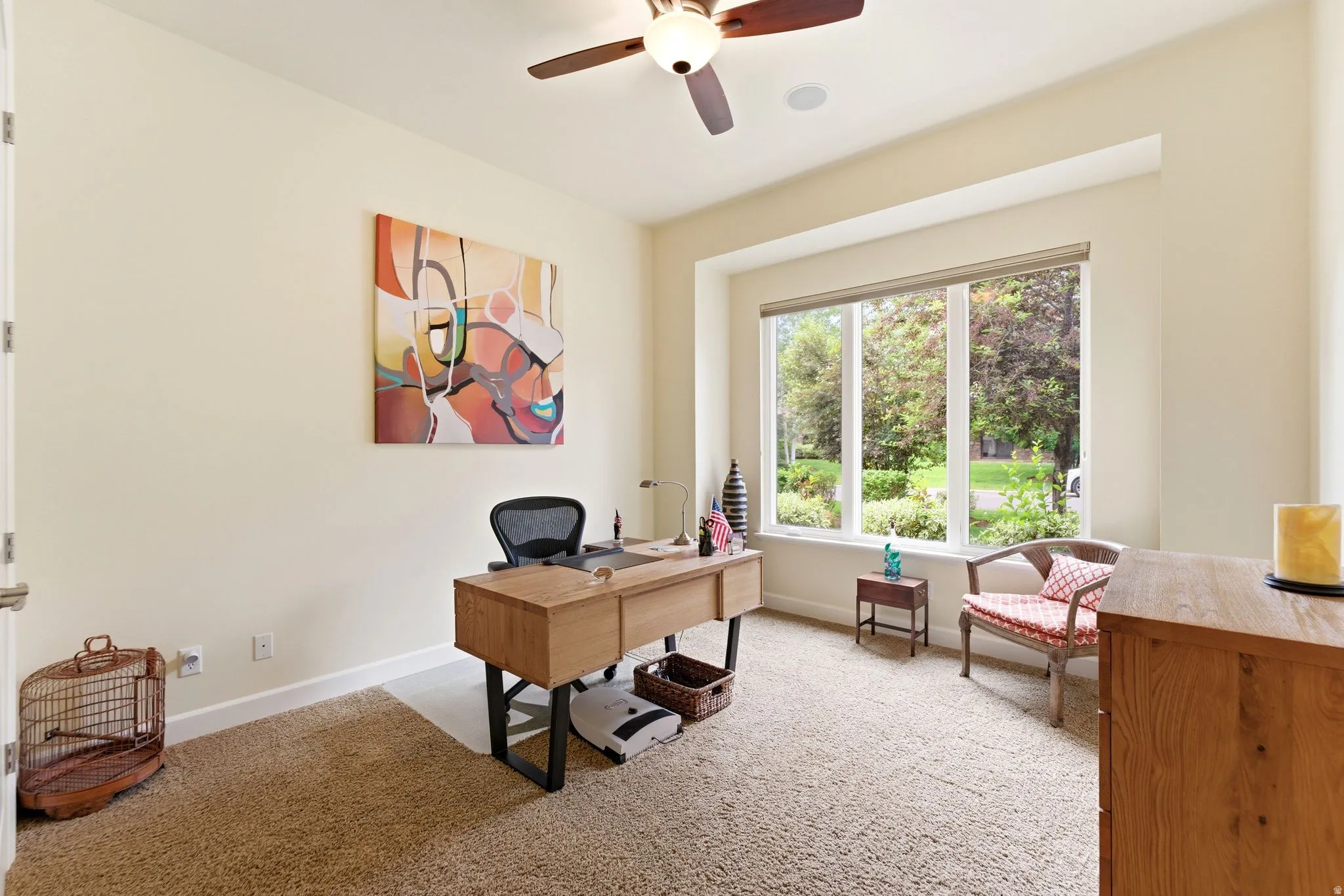 Bright interior space featuring a large window with exterior landscaping, a ceiling fan, and light-toned wall paint