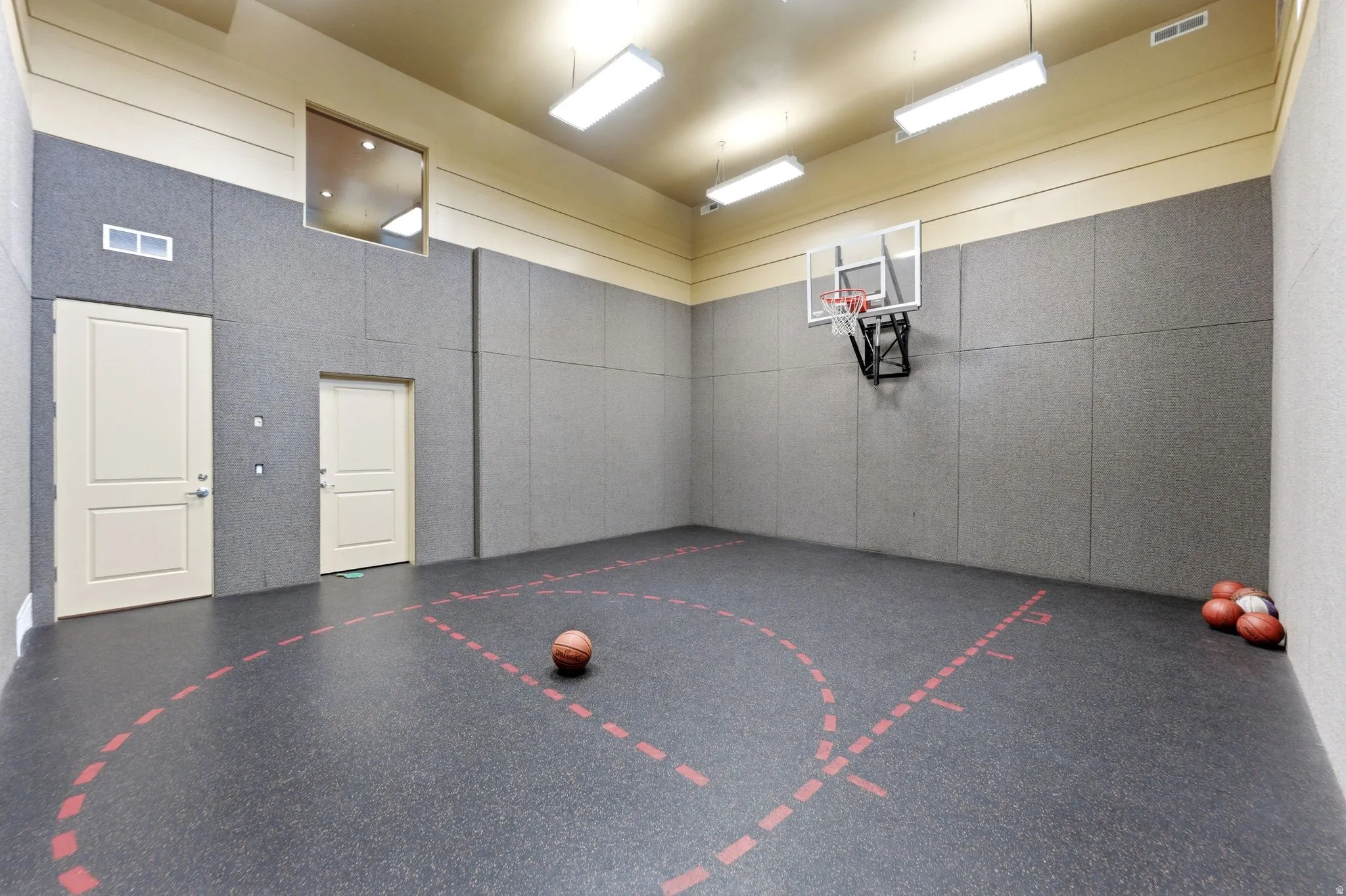 Indoor sports court featuring a mounted basketball hoop and marked court lines
