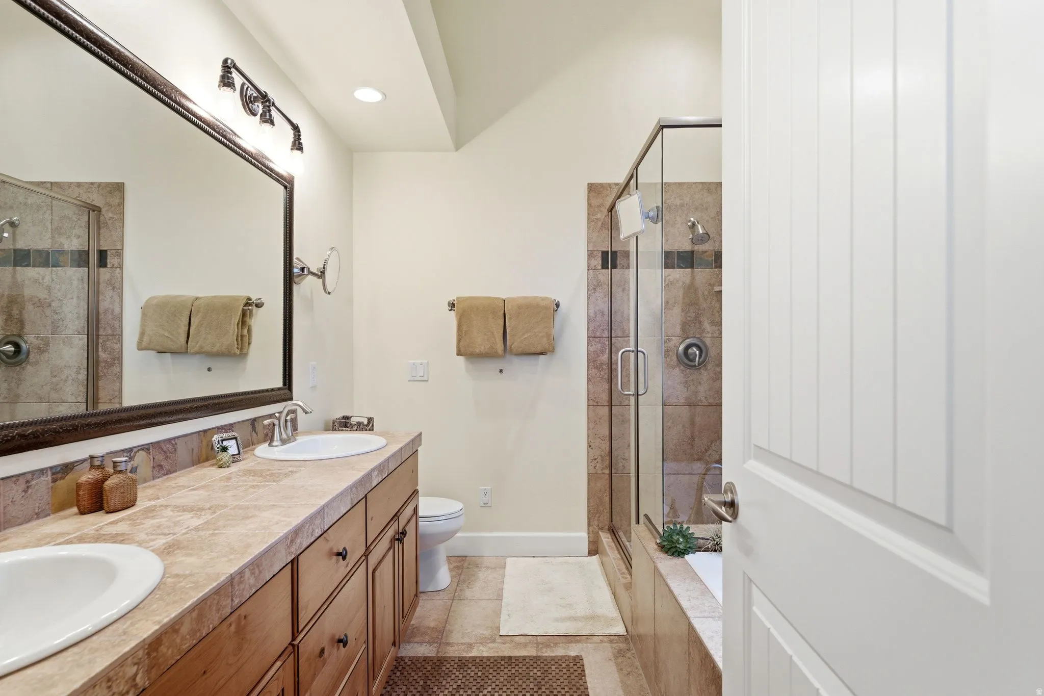 Double vanity with integrated sinks, a wood-finish cabinet, and stone-finish countertops