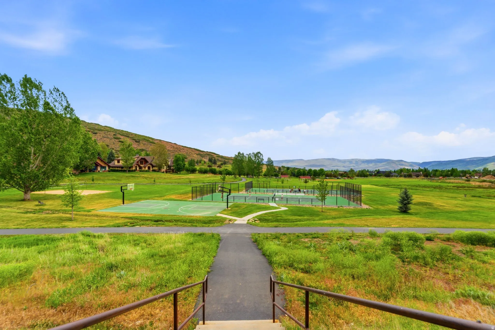 Expansive green space featuring multiple outdoor sports courts, including a basketball court and tennis court Aerial views of Burgi Hill Park adjacent to Valais
