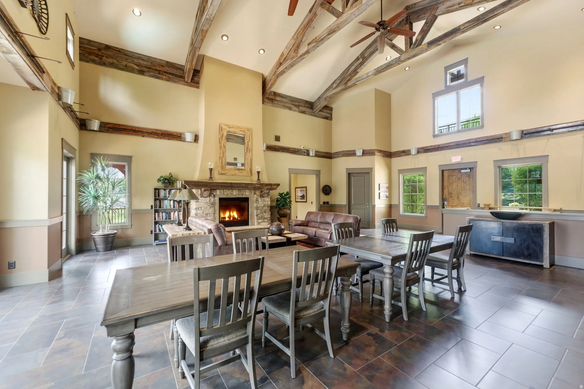 Spacious great room featuring vaulted ceilings with exposed wood beams, a stone-clad fireplace, and large windows