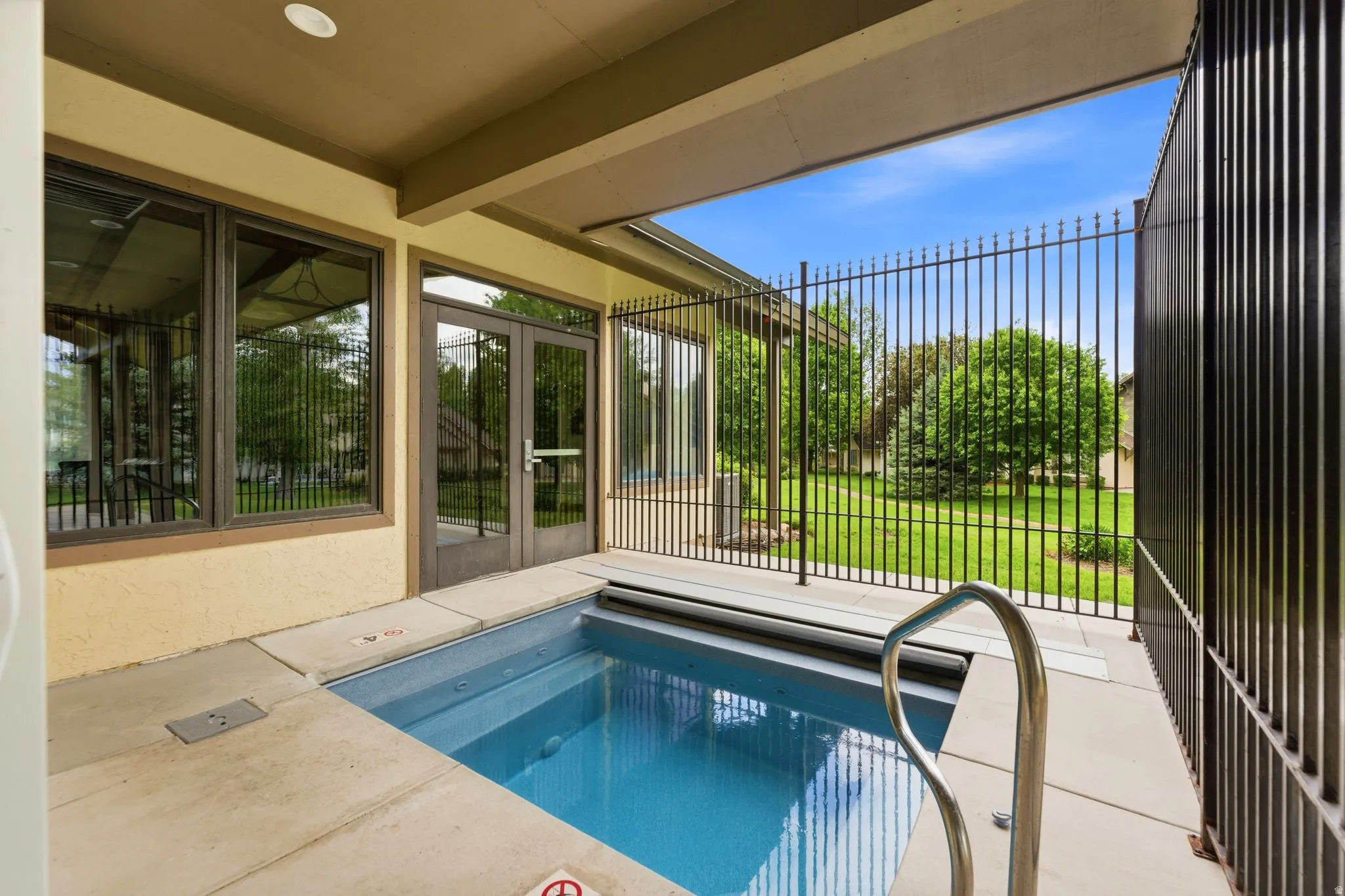 Private plunge pool featuring concrete surround, stainless steel handrail, and secure fencing