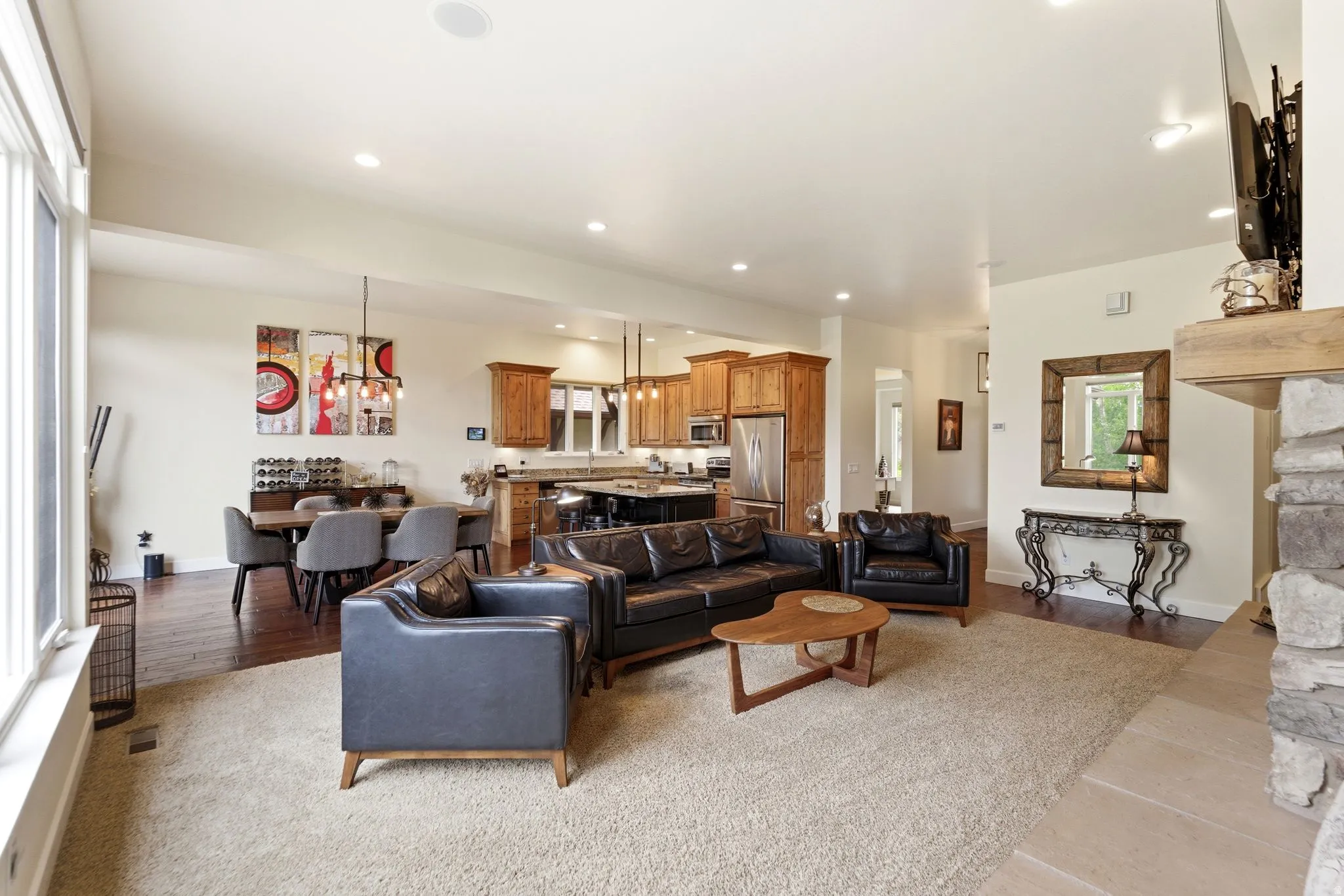 Open-concept living space featuring a stone fireplace, recessed lighting, and wood-finish flooring