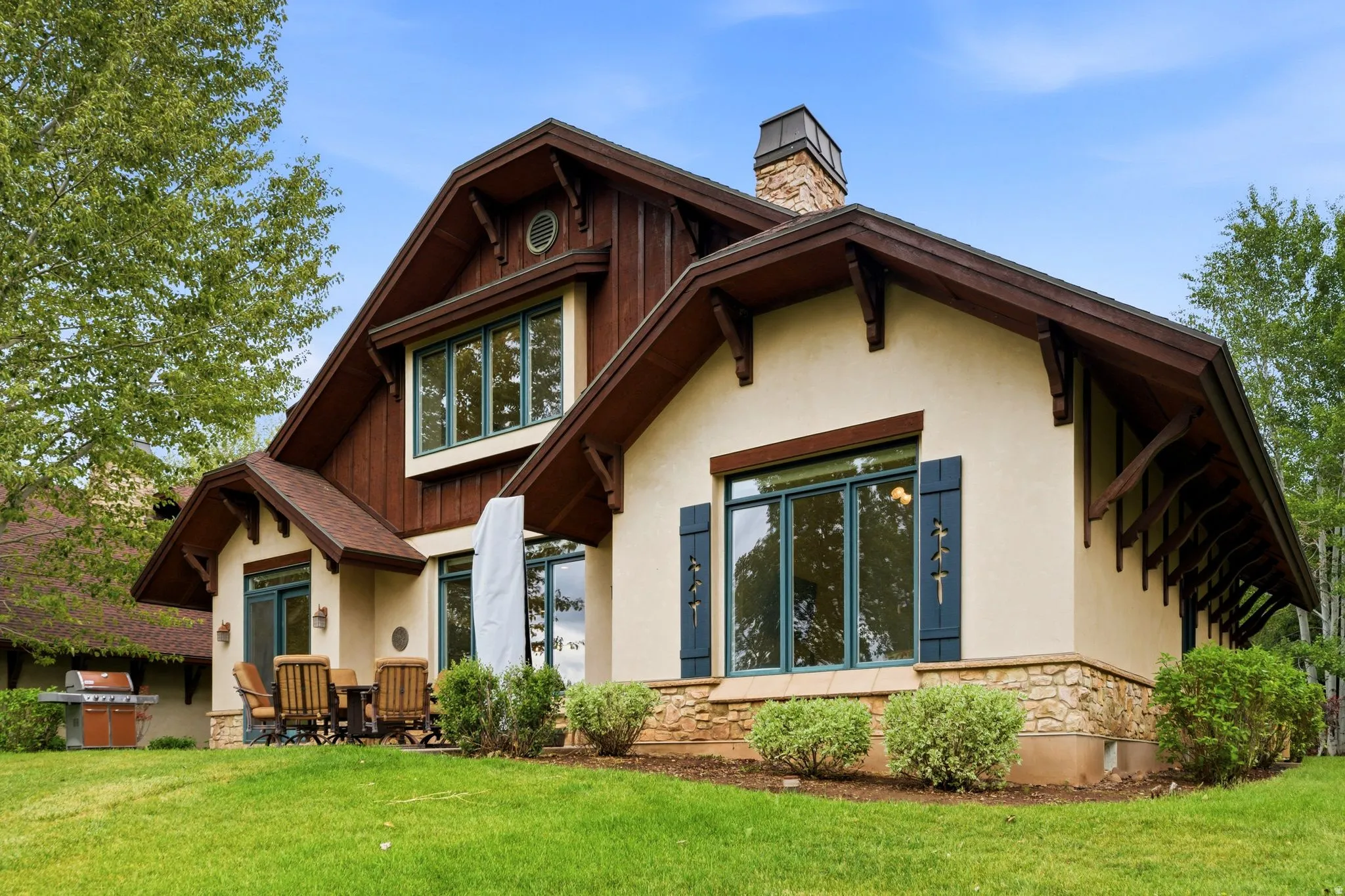 Exterior featuring stucco and wood siding, stone accents, and a prominent stone chimney