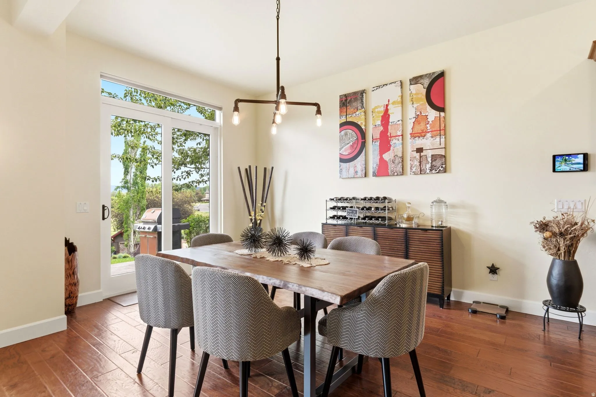 Dining area with wood-finish flooring and a contemporary linear chandelier