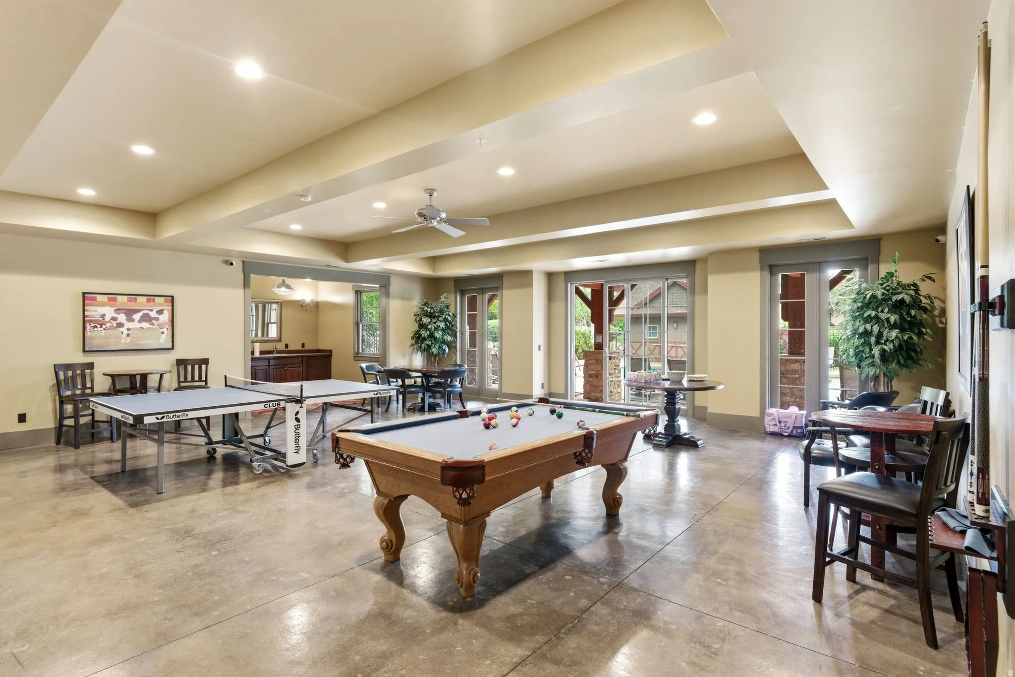 Spacious entertainment room featuring concrete flooring, recessed lighting, and a ceiling fan