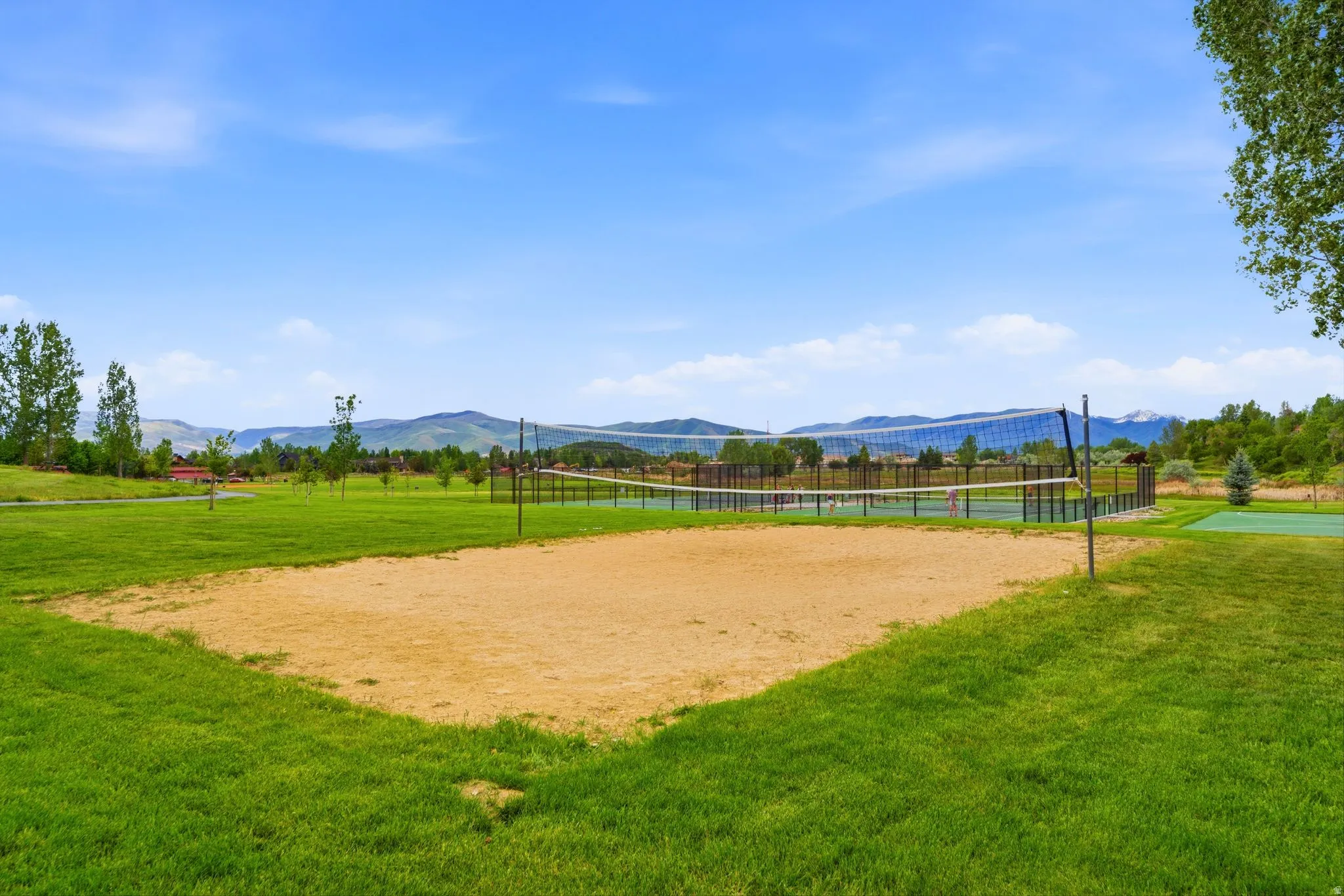 Sand volleyball court set within expansive green space. Aerial views of Burgi Hill Park adjacent to Valais