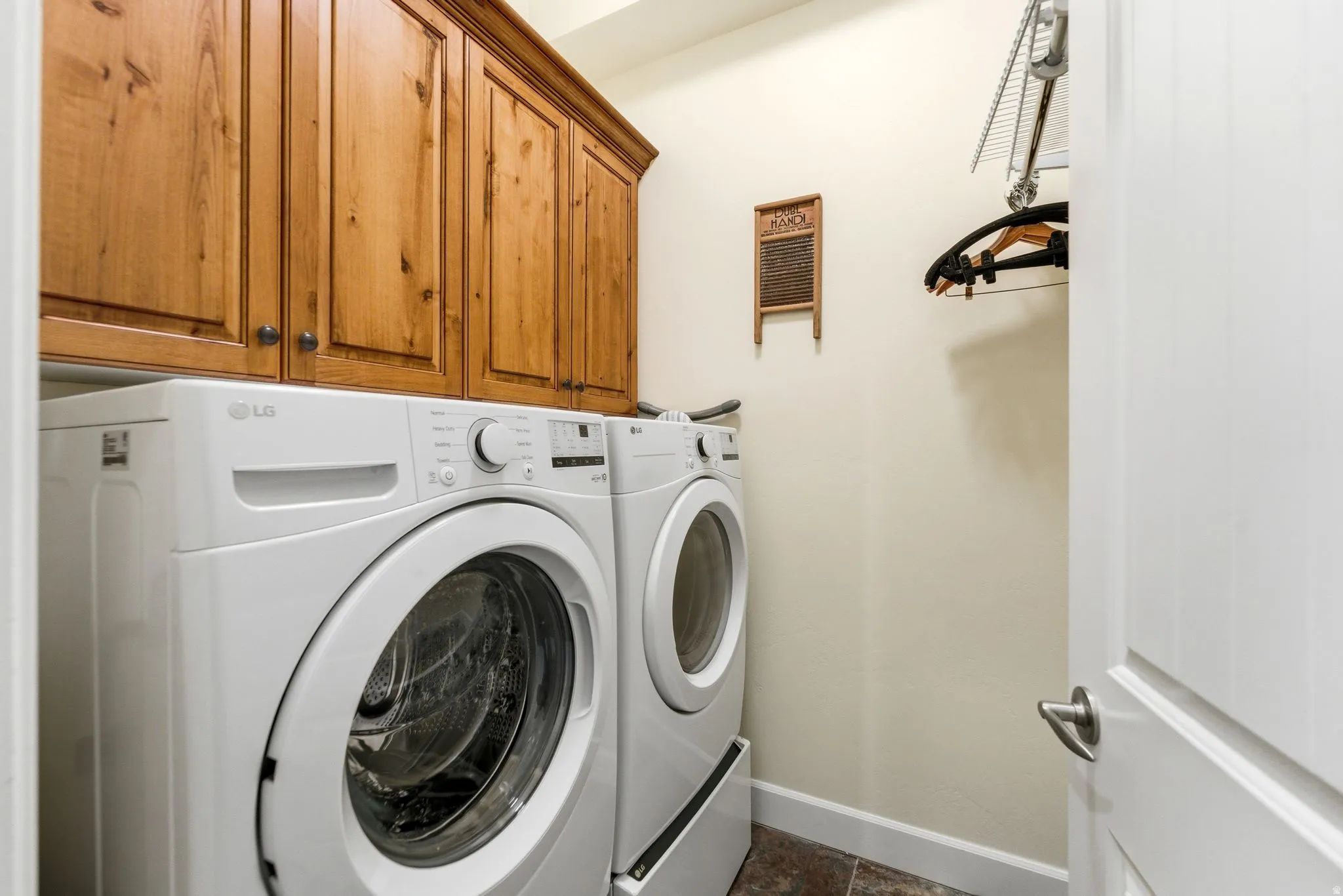Laundry area featuring custom wood cabinetry, tile flooring, and integrated shelving