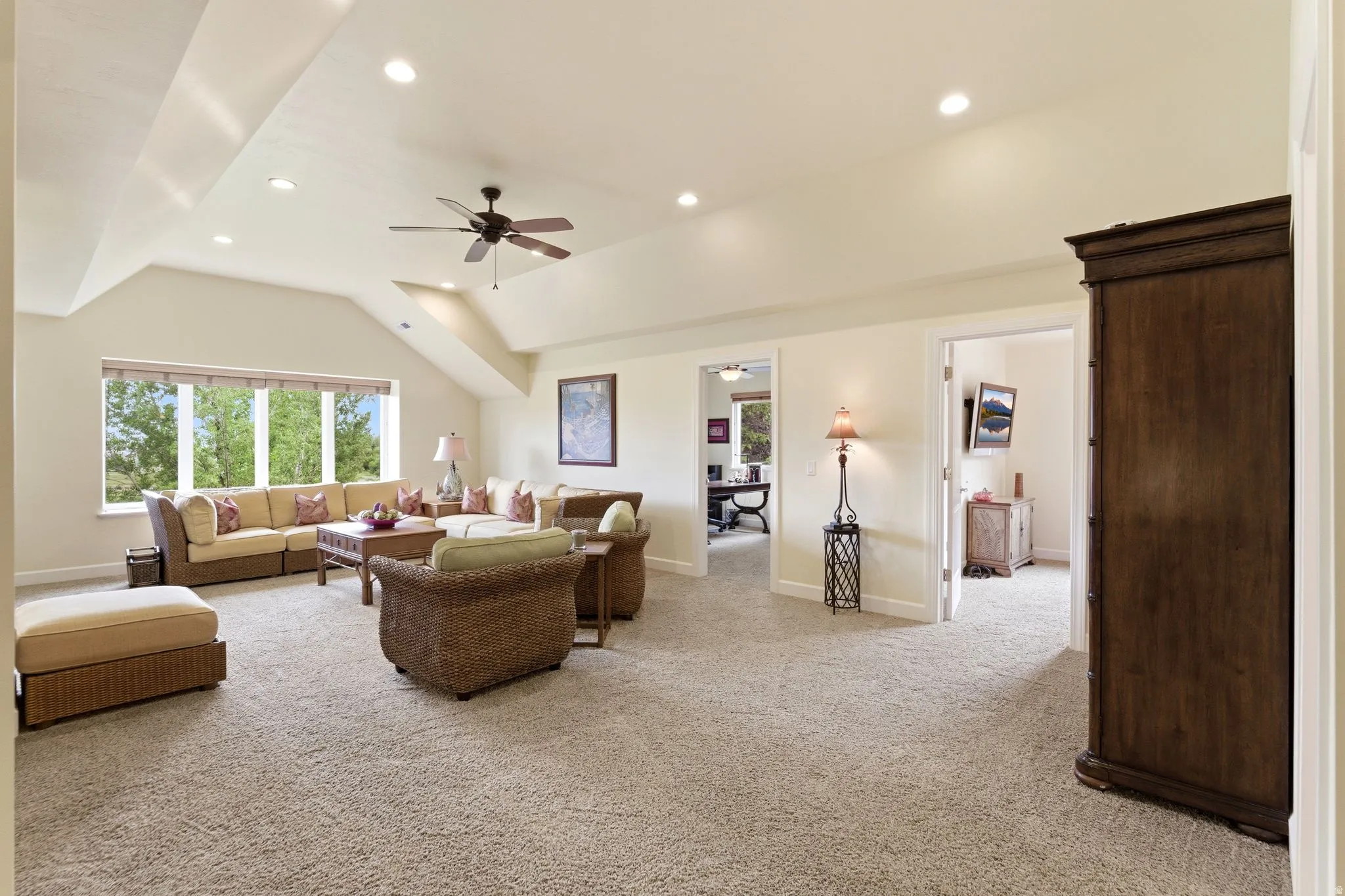Spacious room featuring vaulted ceilings, recessed lighting, a ceiling fan, and carpeted flooring