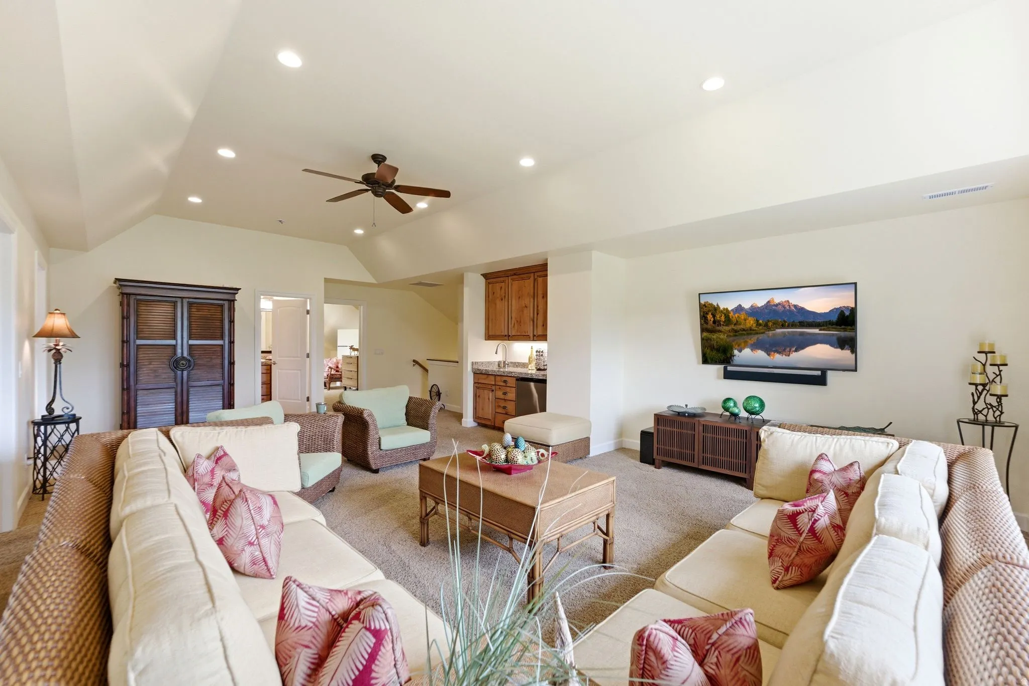Spacious living area featuring neutral carpeting, recessed lighting, a ceiling fan, and a built-in wet bar with wood cabinetry and a countertop