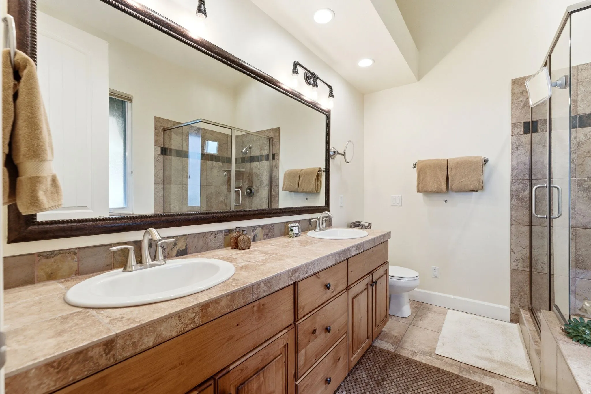 Double vanity with oval undermount sinks and brushed nickel faucets set into a tiled countertop