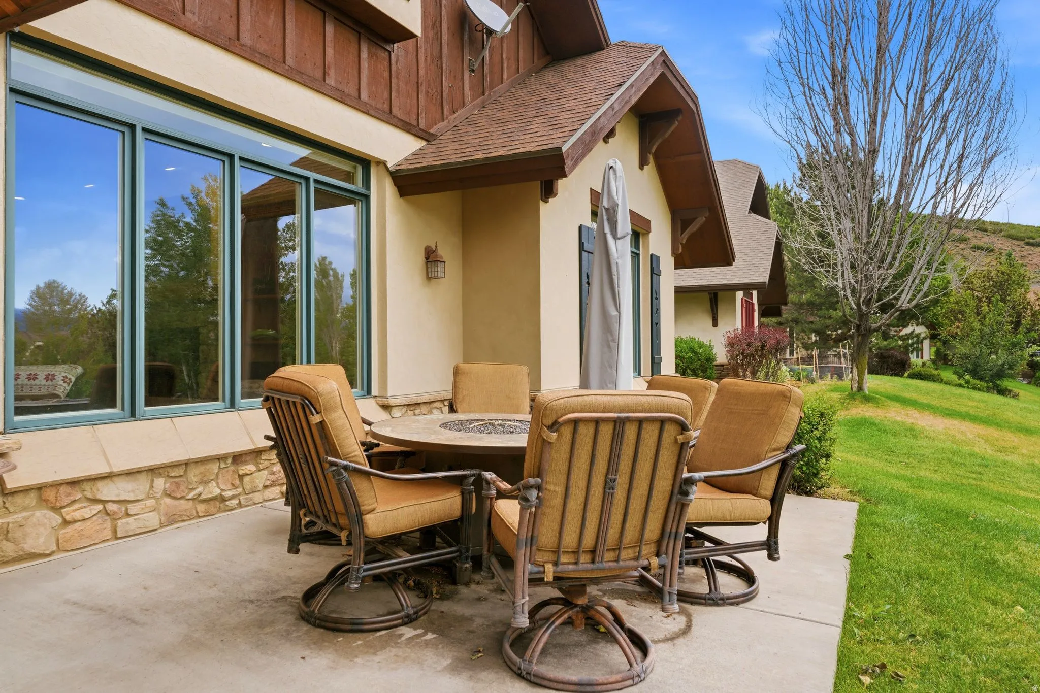 Spacious concrete patio with stucco exterior, stone base detailing, and ample fenestration