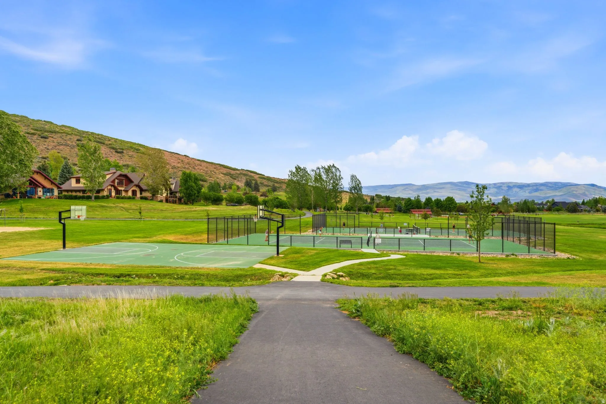 Outdoor recreational area featuring multiple sports courts, including a basketball court and tennis courts, surrounded by expansive green spacesAerial views of Burgi Hill Park adjacent to Valais