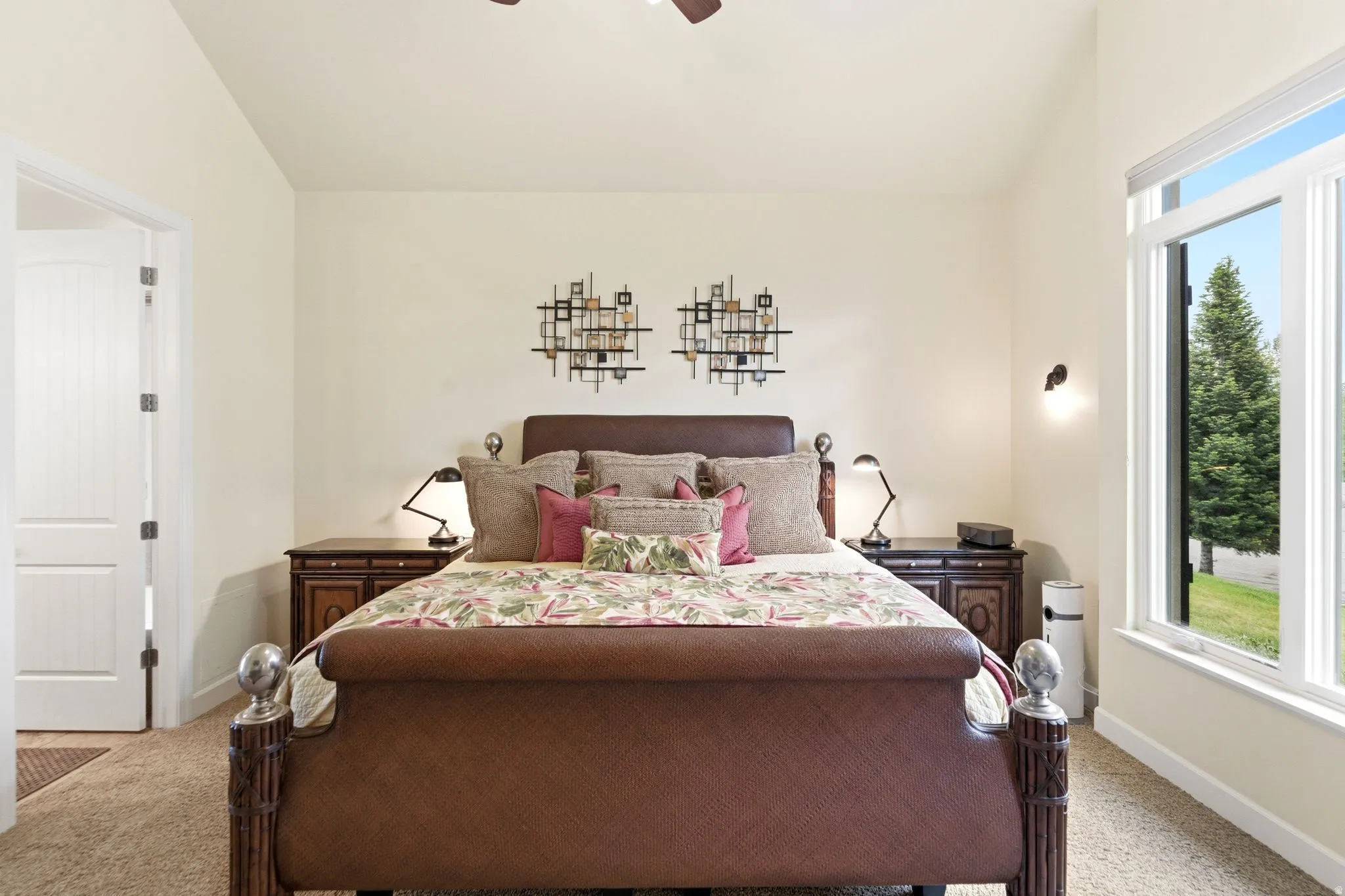 Spacious room featuring vaulted ceilings, a large multi-pane window, wall-mounted sconce lighting, and a paneled interior door