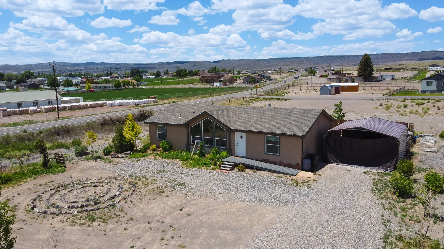Single-story residence featuring a brown exterior, a covered carport, and a gravel driveway