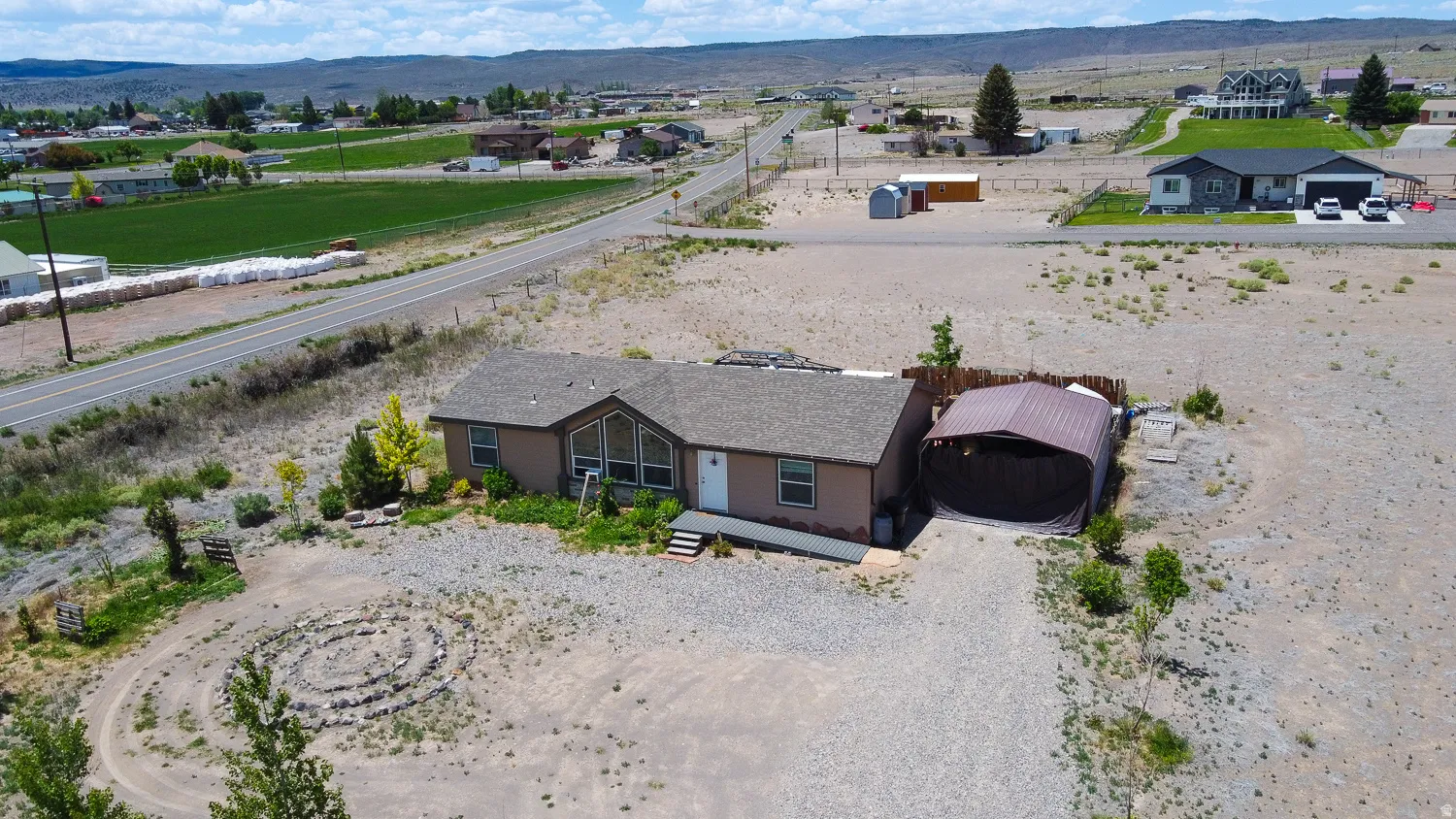 Ranch-style residence featuring a prominent front door, an attached carport, and a gravel driveway