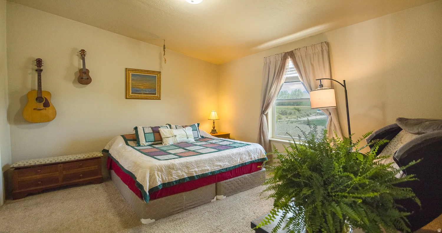 Carpeted bedroom featuring an angled ceiling, a window with exterior scenery, and a built-in overhead light fixture