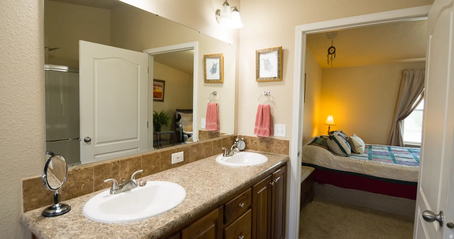 Dual vanity with laminate countertops, integrated sinks, chrome fixtures, and a tile backsplash