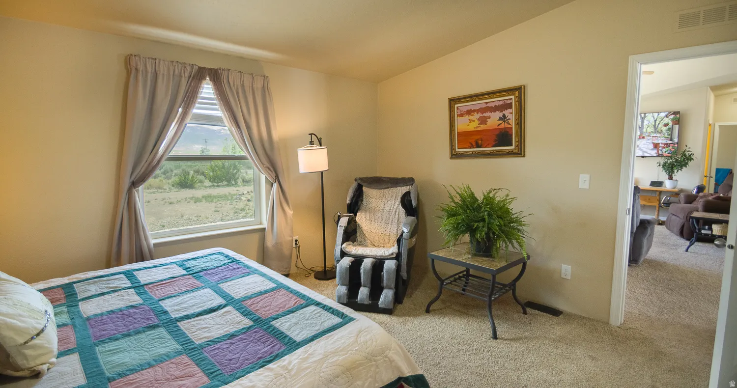 Carpeted room with a large window overlooking natural landscaping