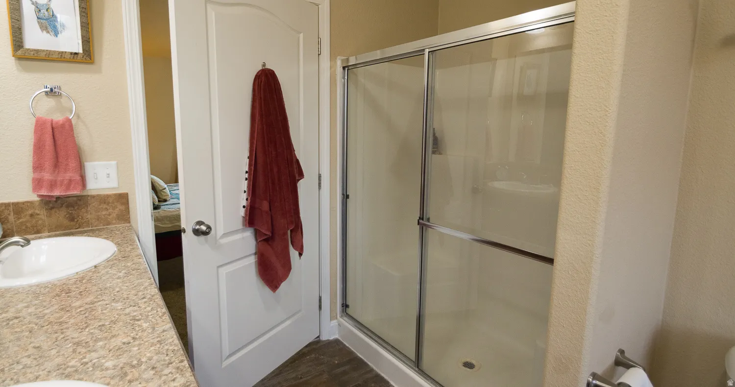Bathroom with a shower enclosure featuring sliding glass doors and a single vanity with an integrated sink and laminate countertop