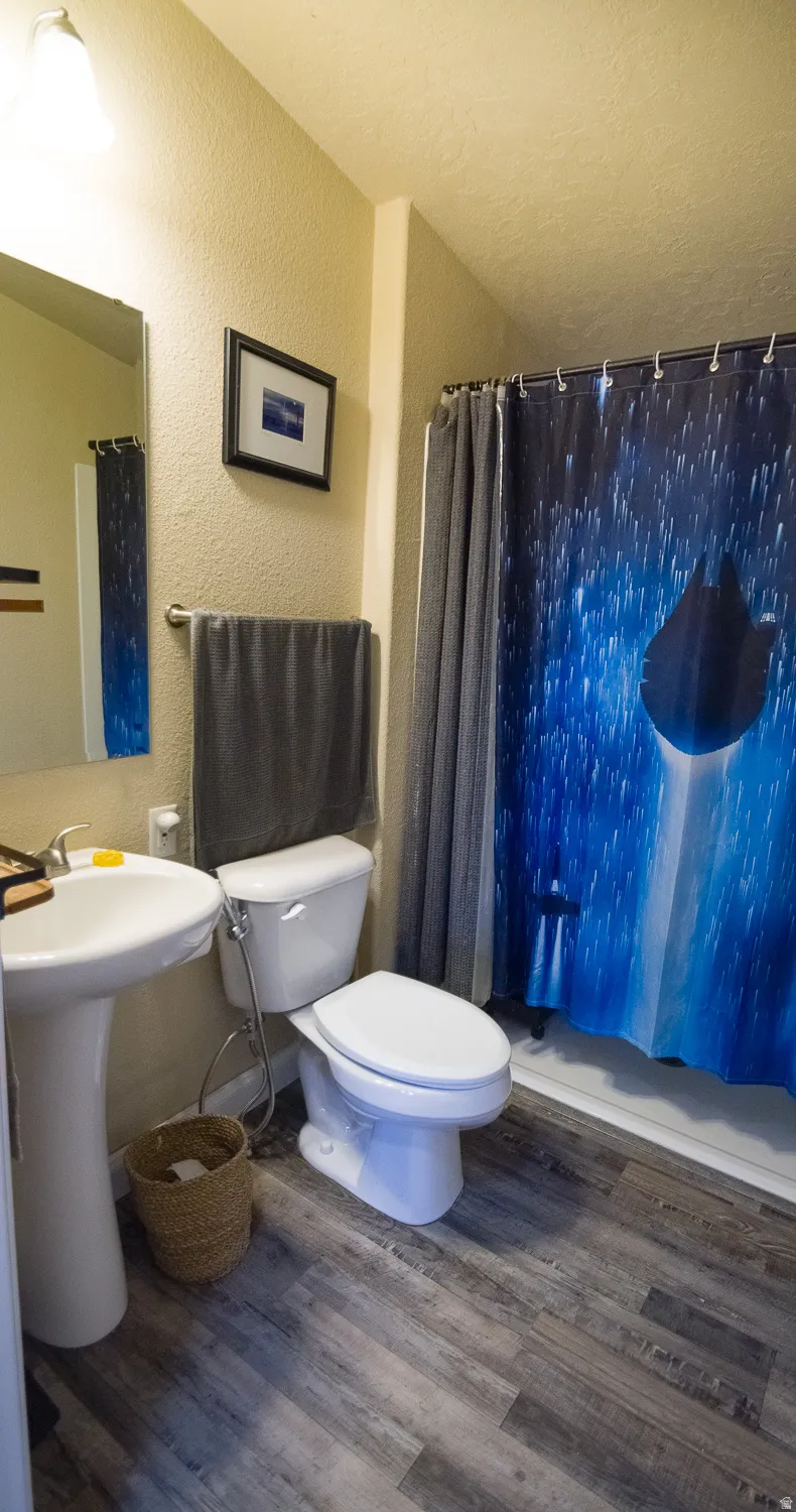 Bathroom featuring a pedestal sink, white toilet, and a combination shower/tub with white surround