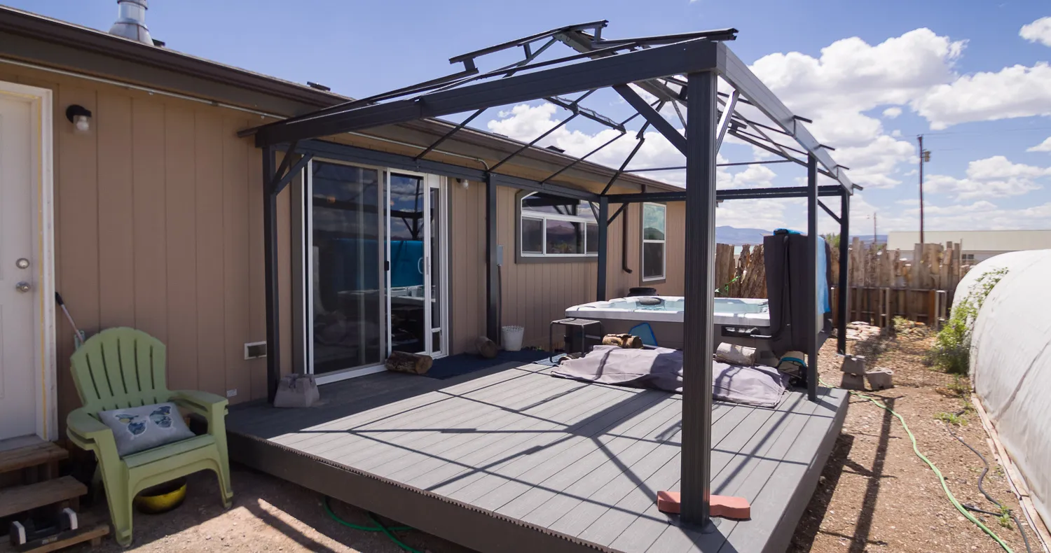 Expansive outdoor deck featuring a hot tub, a pergola structure, sliding glass door access to the interior, and a light brown exterior wall