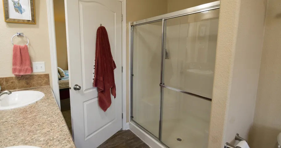 Bathroom with a shower enclosure featuring sliding glass doors and a single vanity with an integrated sink and laminate countertop