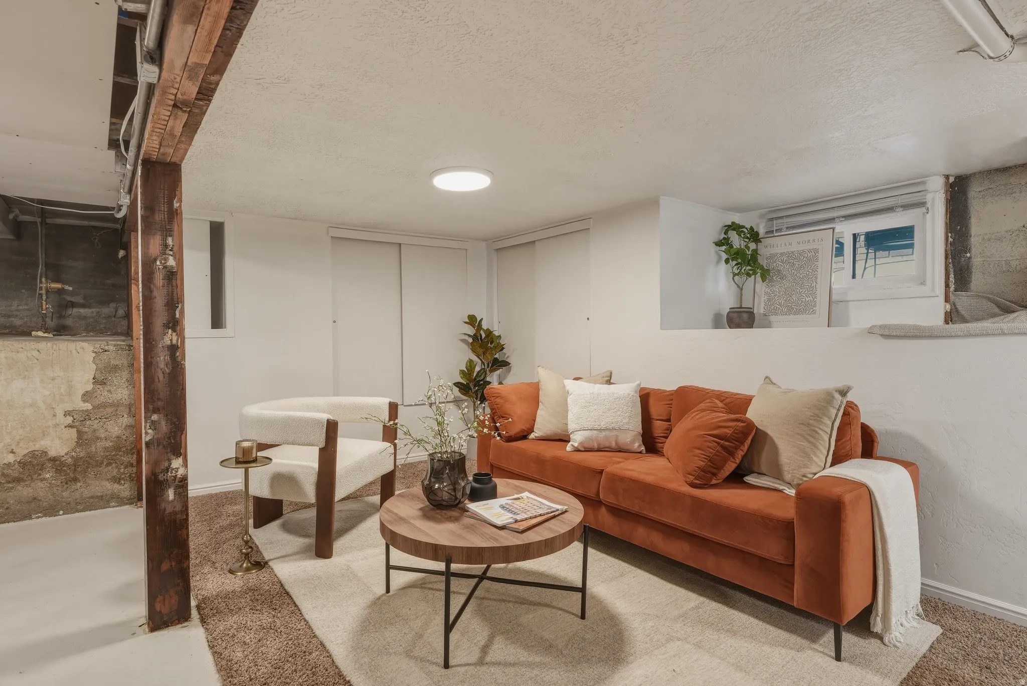 Finished lower level offering an exposed wood support beam, recessed lighting, and a window well for natural illumination