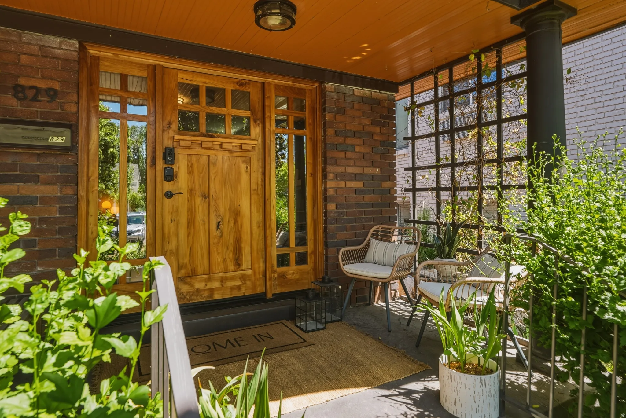 Front entrance featuring a paneled wood door with sidelights, brick façade, and a dark lattice privacy screen
