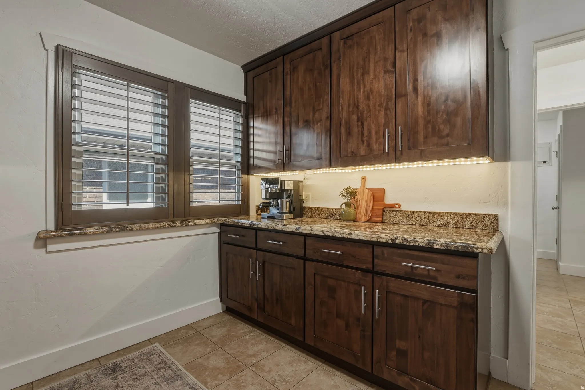 Rich wood-finish cabinetry with stainless hardware, complemented by an under-cabinet lighting system
