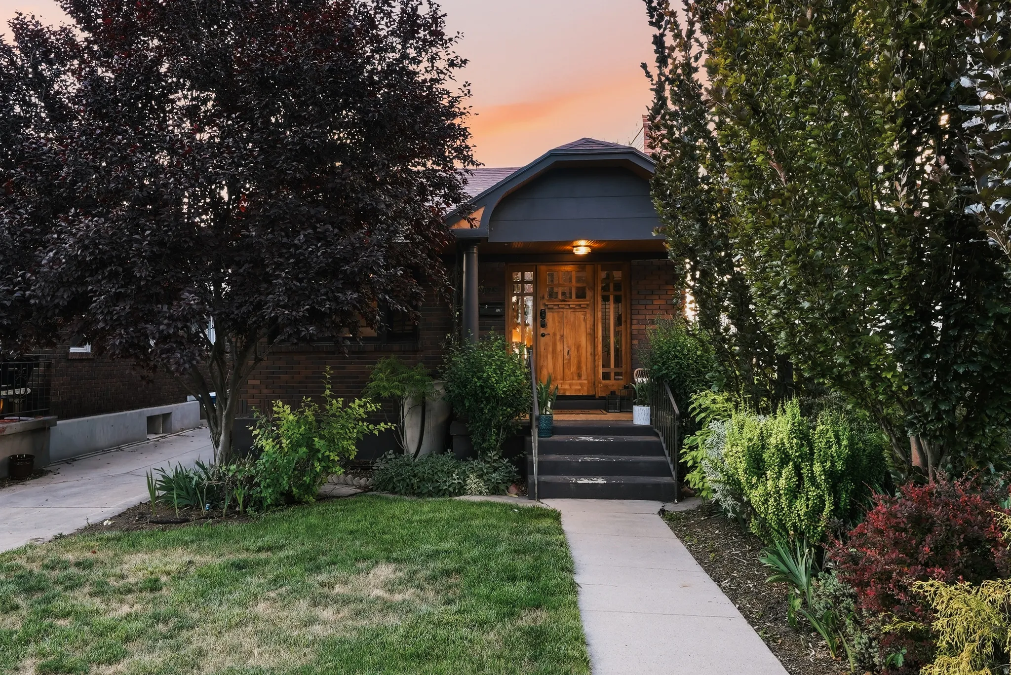 Brick-clad residence featuring a wood entry door with vertical glass panels, a covered porch, and a dark blue-gray roofline