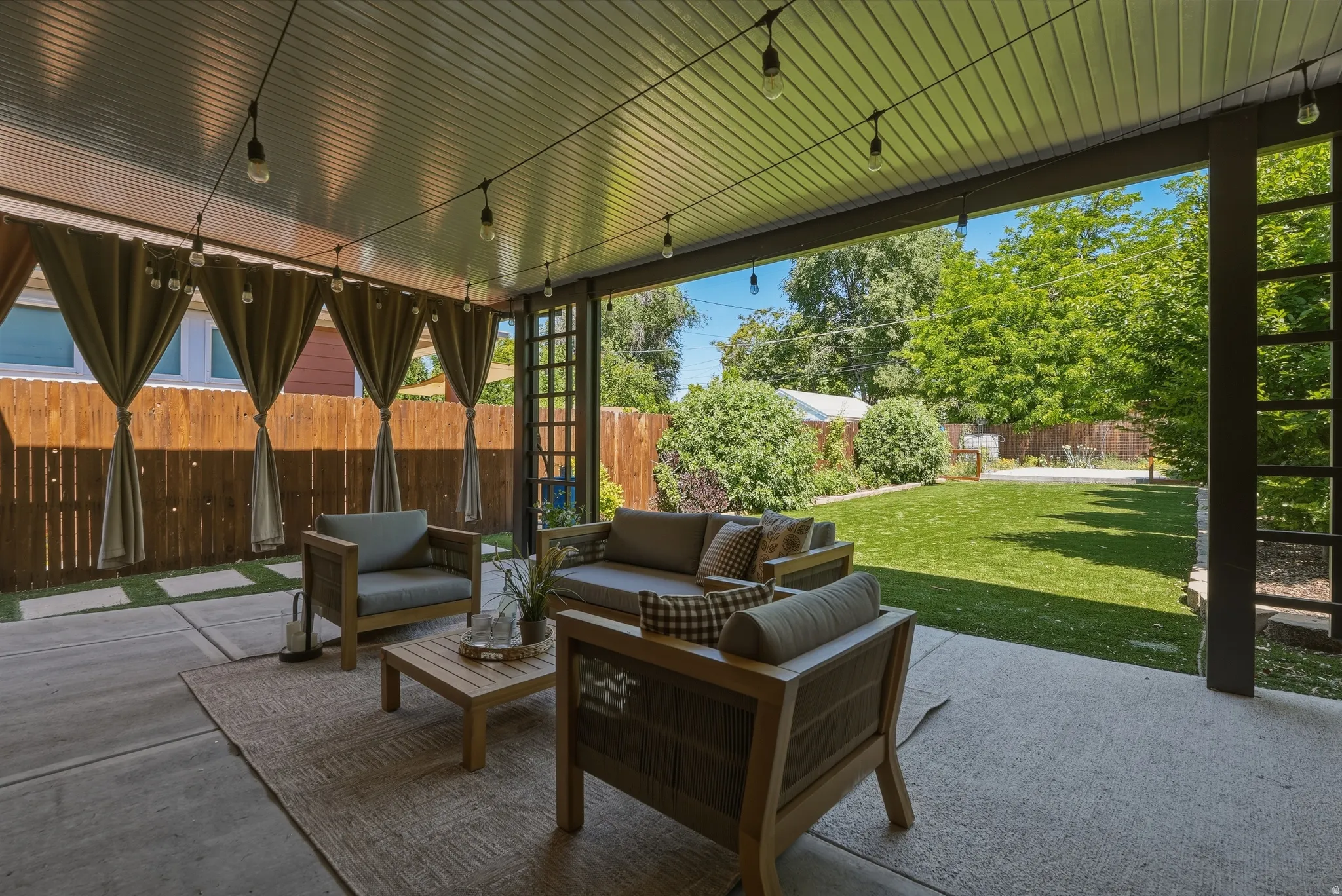 Covered patio featuring string lights, concrete flooring, and a trellised accent wall