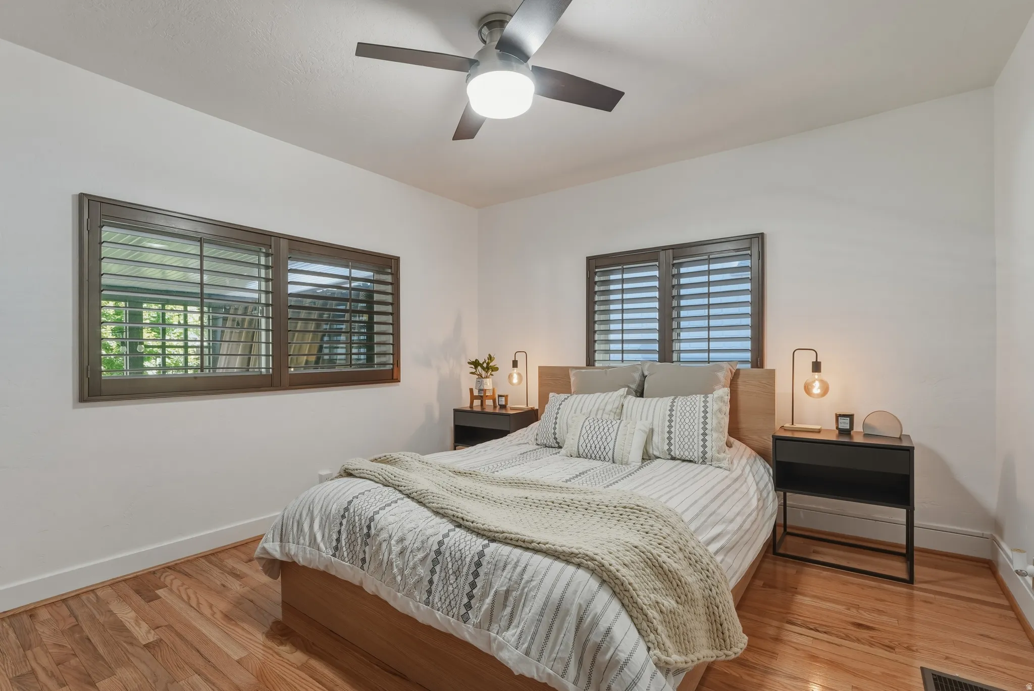 Bright interior space featuring wood-finish flooring, white baseboards, and a ceiling fan with integrated lighting
