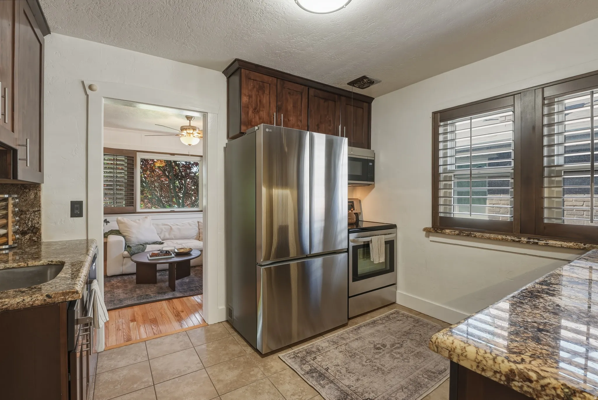 Kitchen featuring stainless steel appliances, dark wood-finish cabinetry, and granite countertops