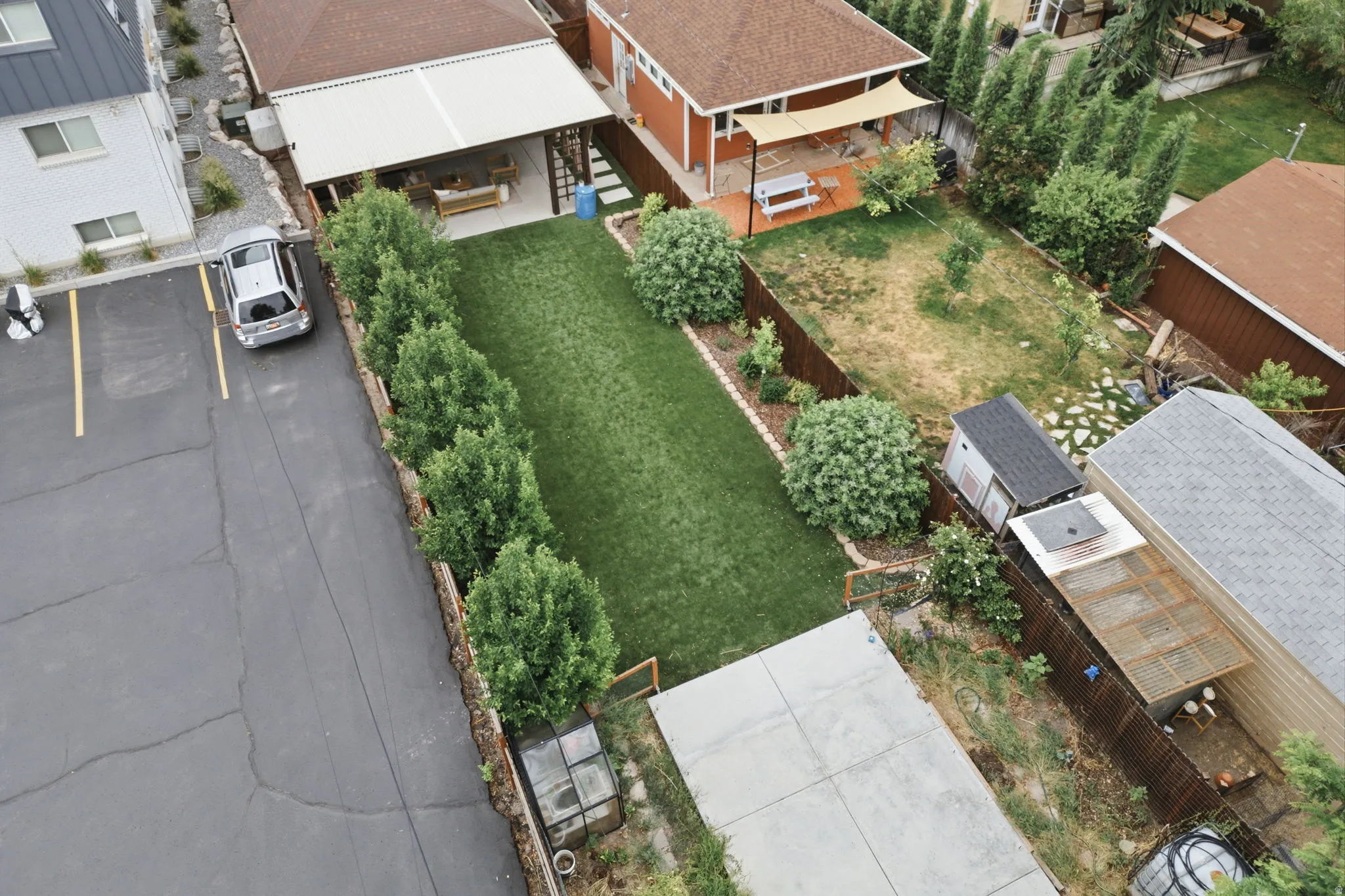 Expansive green lawn bordered by mature shrubs and a wood fence
