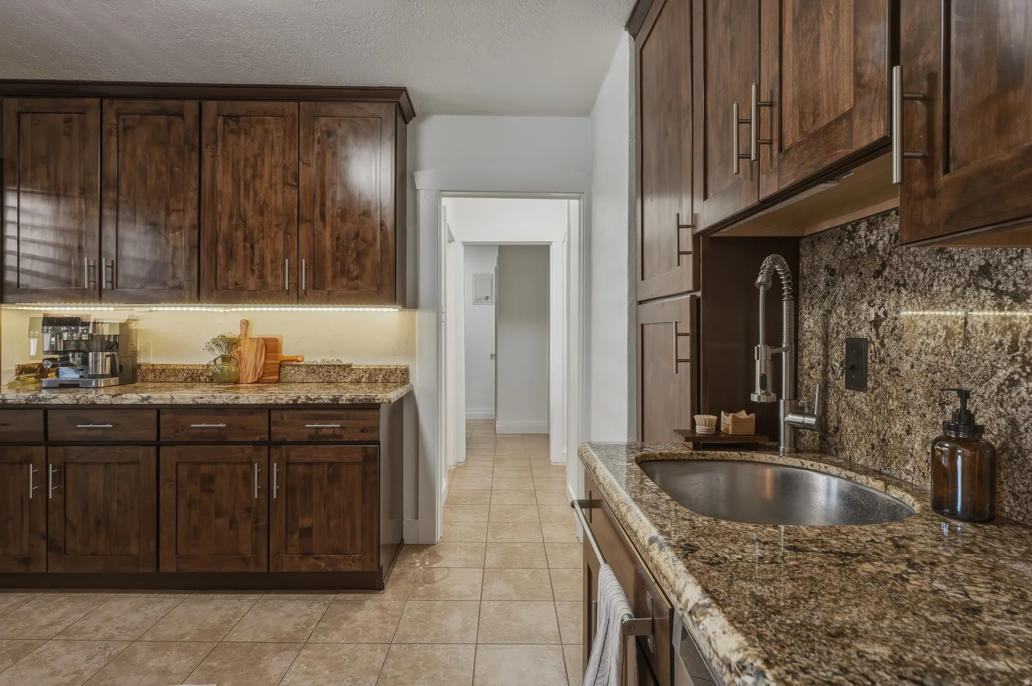 Kitchen featuring wood cabinetry, granite countertops, tile flooring, an undermount sink, and a pull-down faucet