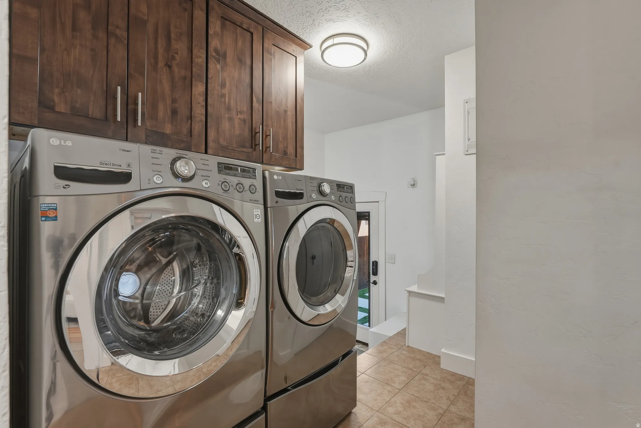 Laundry area featuring dark wood-finish cabinetry, tile flooring, and a contemporary ceiling light fixture