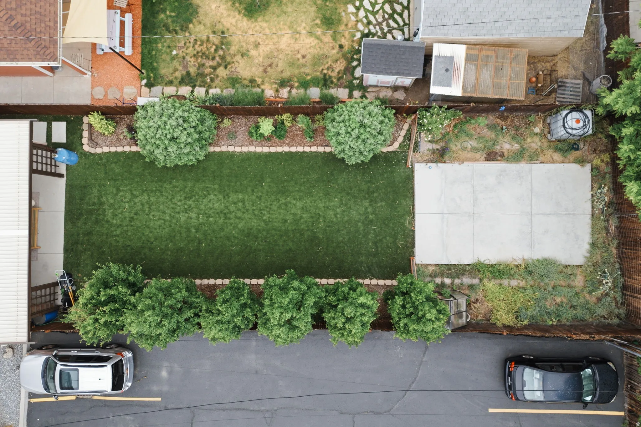 Expansive backyard featuring a rectangular lawn area, mature shrubbery, and a concrete patio