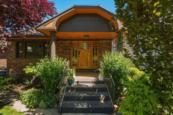 Brick exterior featuring a distinctive covered entry with a natural wood door and sidelights