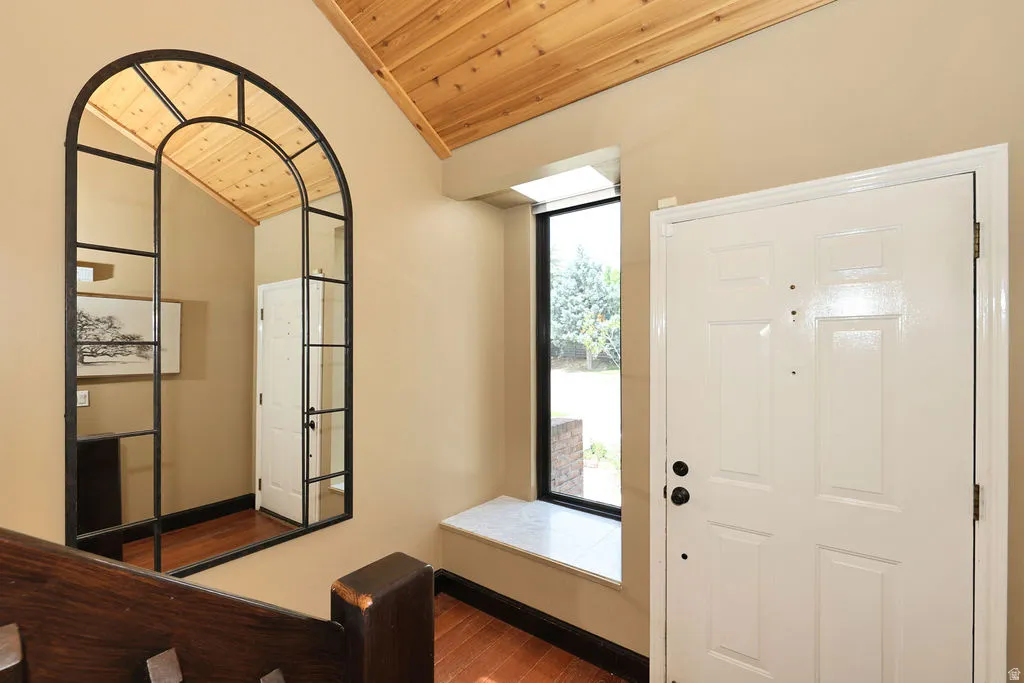 Vaulted wood-paneled ceiling, wood-finish flooring, and a large arched mirror with black framing